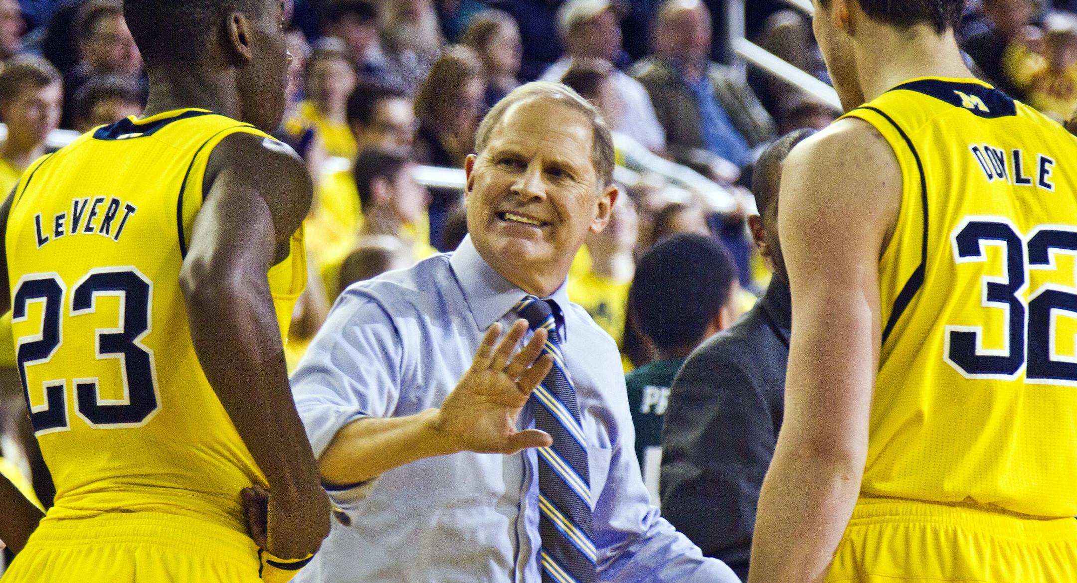 Michigan head coach John Beilein, center, gives instructions to guard Caris LeVert (23) and forward Ricky Doyle (32) during a timeout in the second half of an NCAA college basketball game against Eastern Michigan at Crisler Center in Ann Arbor, Mich., Tuesday, Dec. 9, 2014. Eastern Michigan won 45-42. (AP Photo/Tony Ding) ORG XMIT: MITD105