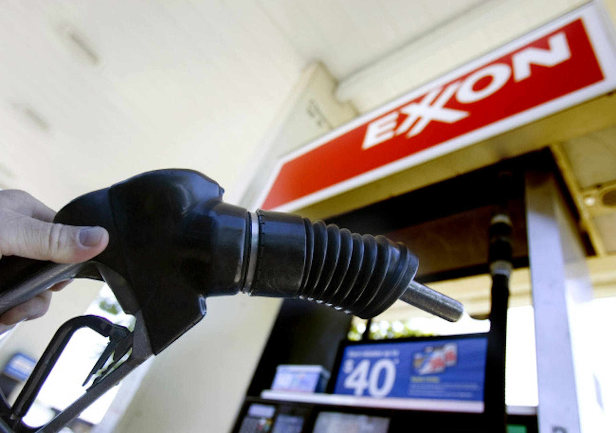 In this July 31, 2008 file photo, a customer holds a gas pump handle at an Exxon station in Vancouver, Wash. Exxon Mobil Corp. sets quarterly profit record for U.S corporations at $14.83 billion, Thursday, Oct. 30, 2008.