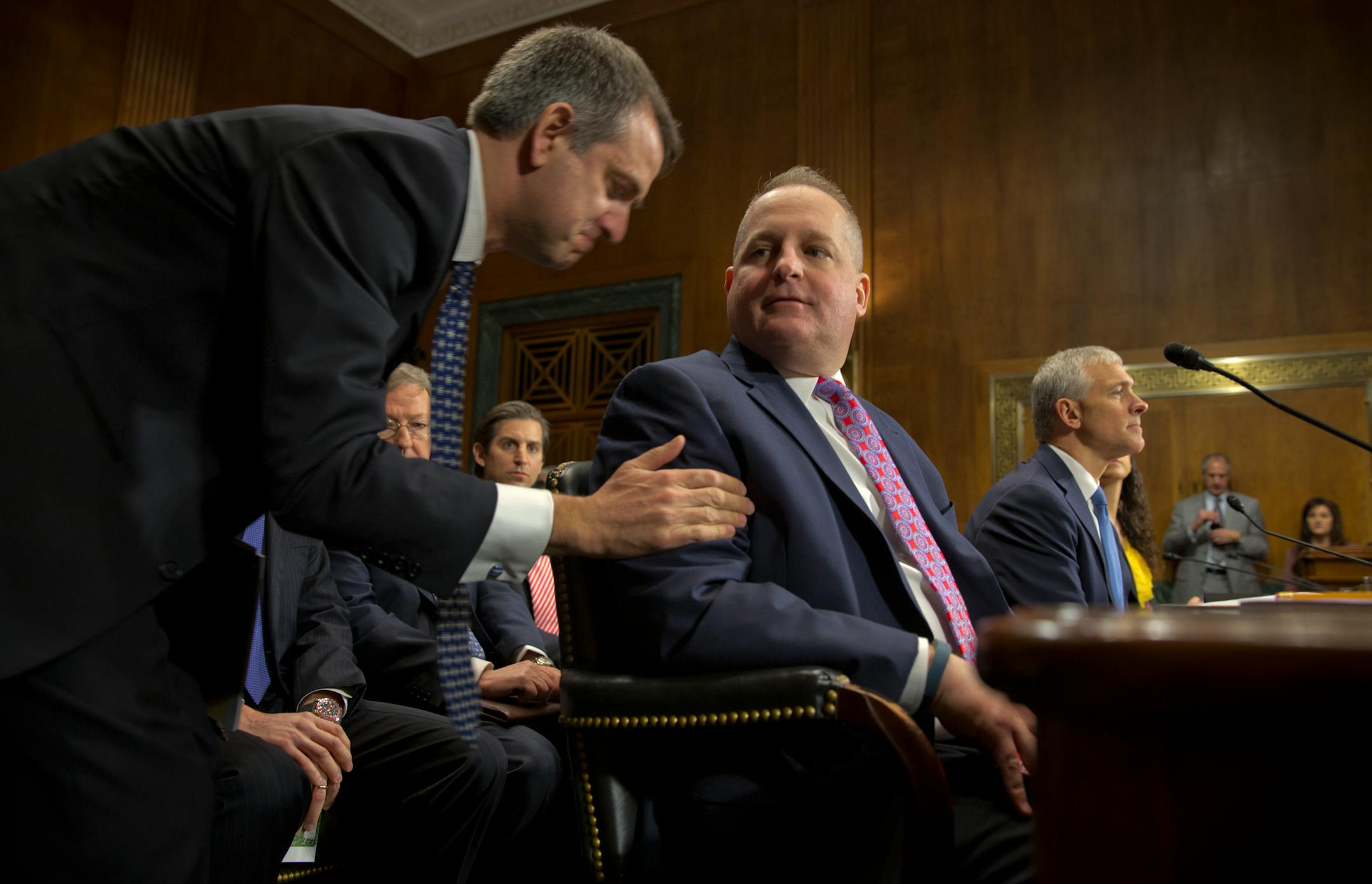 In this January 2014 file photo, Stuart Ingis of Venable LLP, left, speaks with John Mulligan, the chief financial officer of Target, at a Senate Judiciary Committee meeting on Capital Hill in Washington, Jan. 4, 2014. The testimony focused on preventing data breaches and cybercrime comes amid reports of consumers using more cash and less credit in the wake of the widespread theft of credit card data.
