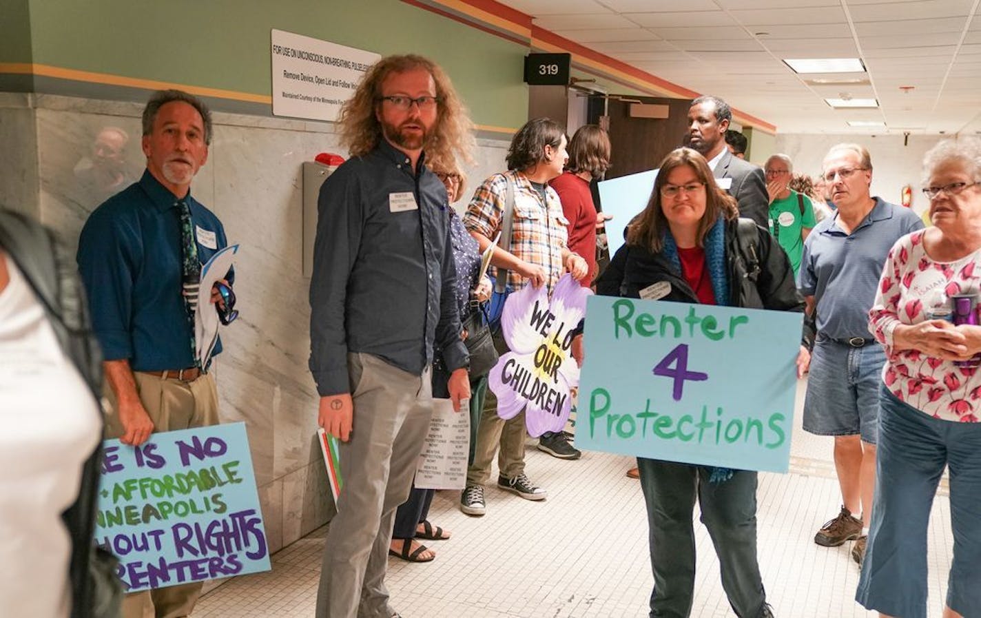 Renters advocacy groups passed out signs outside Minneapolis Council chambers before a hearing on the tenant screening ordinance in August.