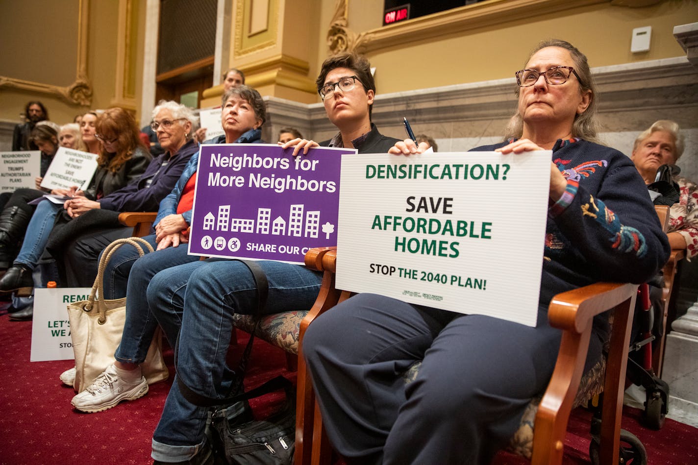 Nancy Przymus, from right, holds a sign against the 2040 Comprehensive Plan, as her neighbor Blue Delliquanti holds a sign supporting the plan during the meeting. ] LEILA NAVIDI • leila.navidi@startribune.com