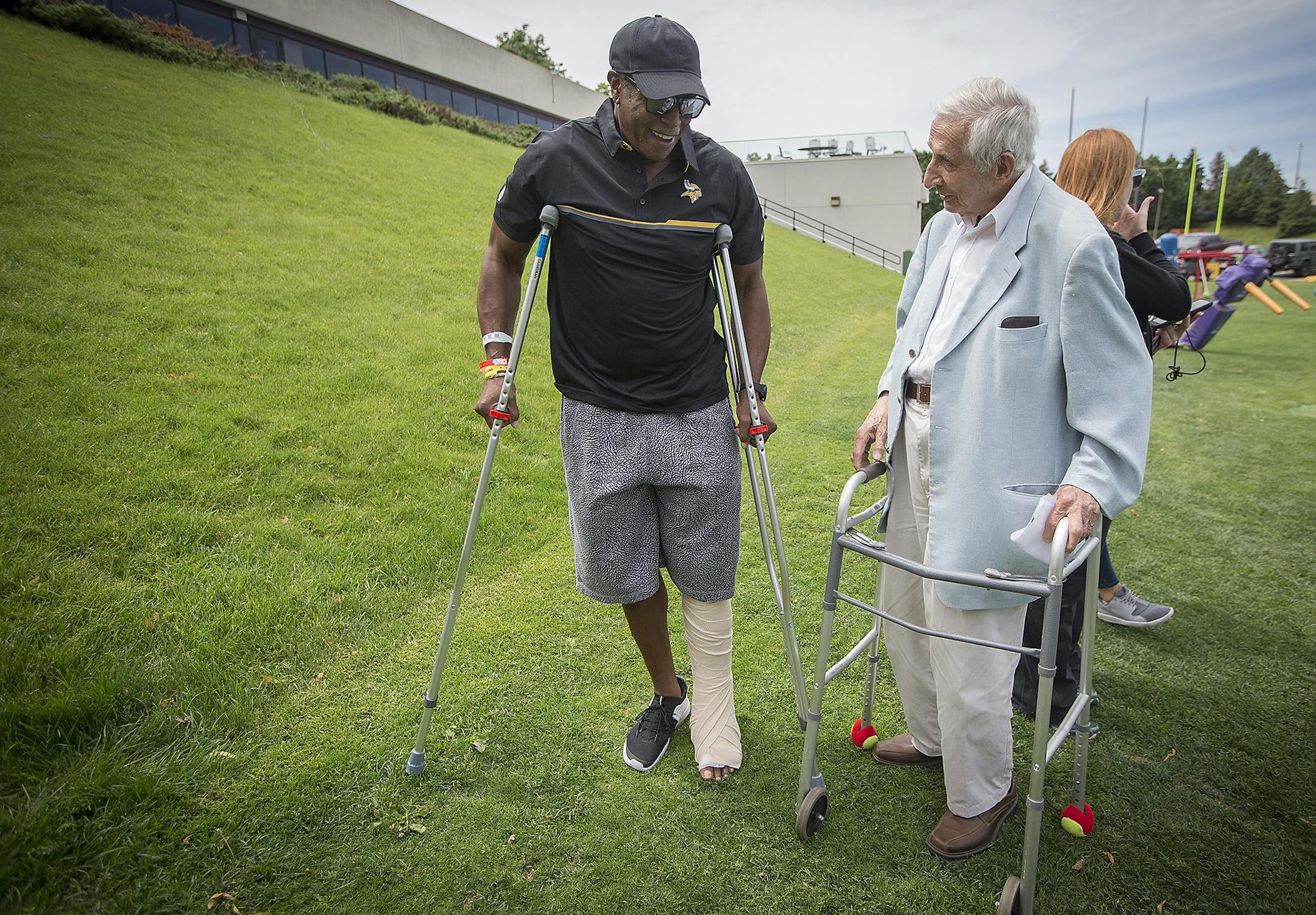 Legendary wide receiver Ahmad Rashad compared his crutches with Star Tribune's Sid Hartman's walker as they made their way to a press conference on the practice field at Winter Park, Wednesday, June 14, 2017 in Eden Prairie, MN.