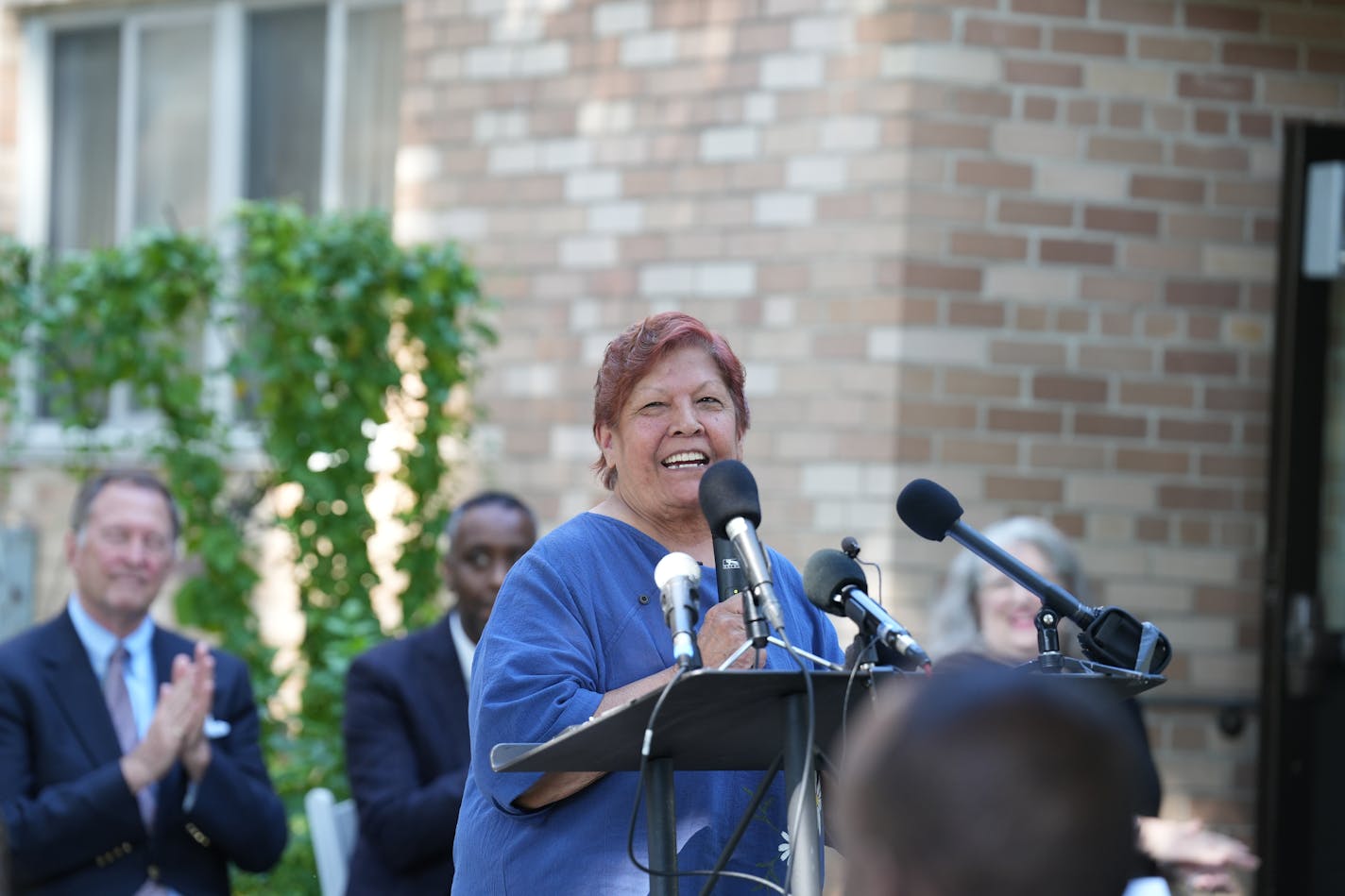 Mary McGovern, public housing tenant and president of the Minneapolis Highrise Representative Council, stands before a microphone speaking at a gathering of elected officials and Minneapolis Public Housing Authority staff Monday to celebrate the installation of sprinklers across the agency's portfolio of 42 high-rise buildings. Four years ago, only 16 buildings were outfitted with fire suppression systems.