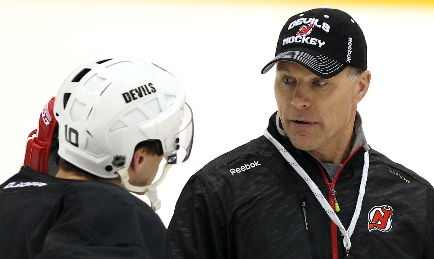 New Jersey Devils coach Scott Stevens, right, talks with defenseman Peter Harrold (10) during a practice on Saturday, Dec. 27, 2014, in Newark, N.J. Devils are replacing the fired Pete DeBoer with a three-headed coaching staff. Former Washington Capitals coach Oates, ex-Devils assistant and star defenseman Stevens and general manager Lou Lamoriello will split duties on the bench. (AP Photo/Adam Hunger) ORG XMIT: NJAH109