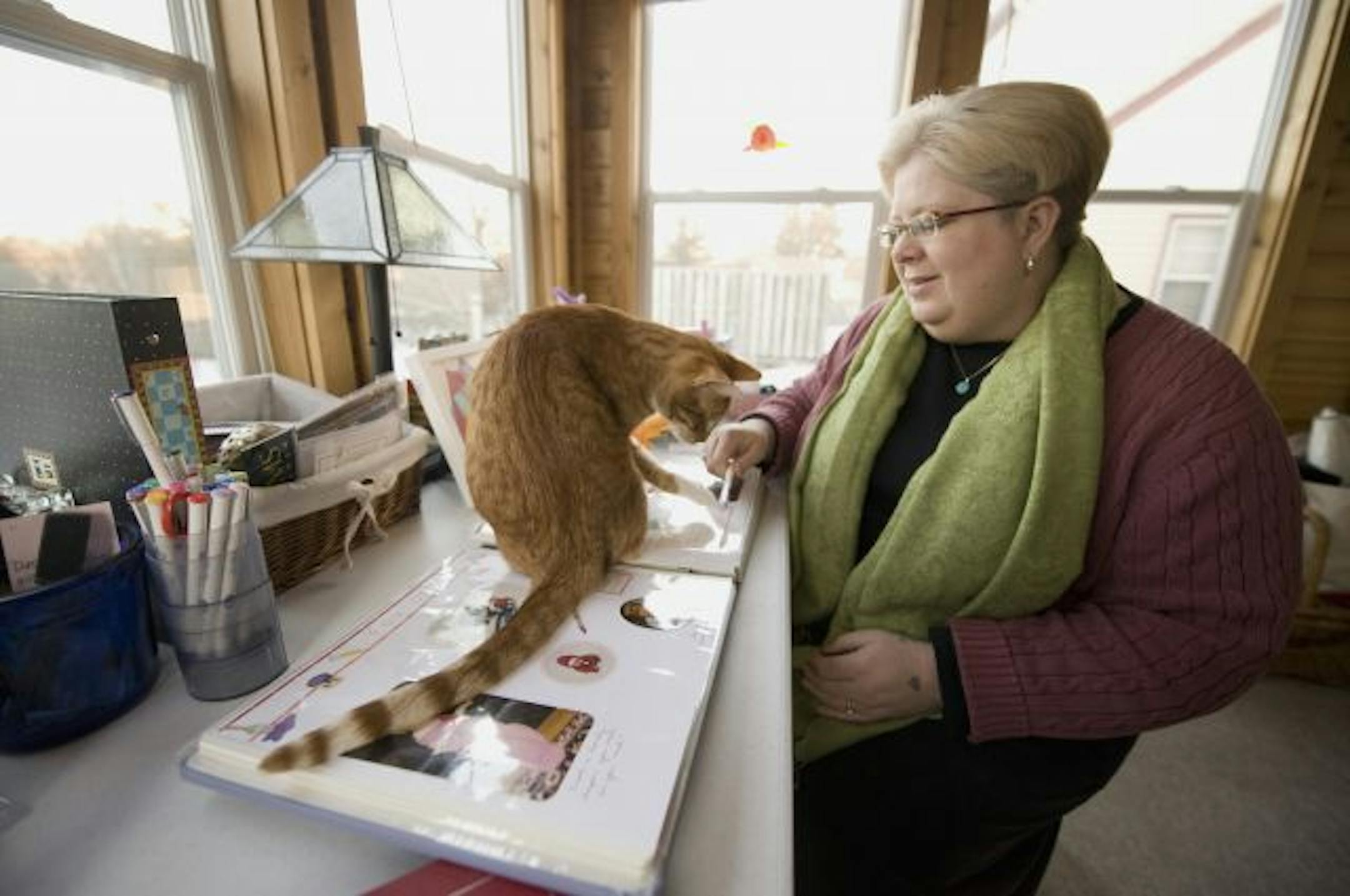 Rene Myers Kelley in her sunroom where she works with one of her cats, Ollie.