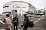 FILE - In this March 12, 2020, file photo, people talk outside Rogers Place, the home ice of the NHL hockey club Edmonton Oilers, in Edmonton, Alberta
