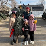 The family of Harper Moyski, far right, poses with their Christmas tree at the Annunciation tree lot in December 2024.