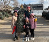 The family of Harper Moyski, far right, poses with their Christmas tree at the Annunciation tree lot in December 2024.