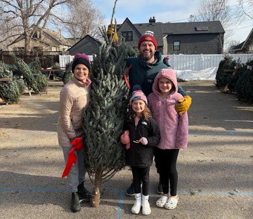The family of Harper Moyski, far right, poses with their Christmas tree at the Annunciation tree lot in December 2024.