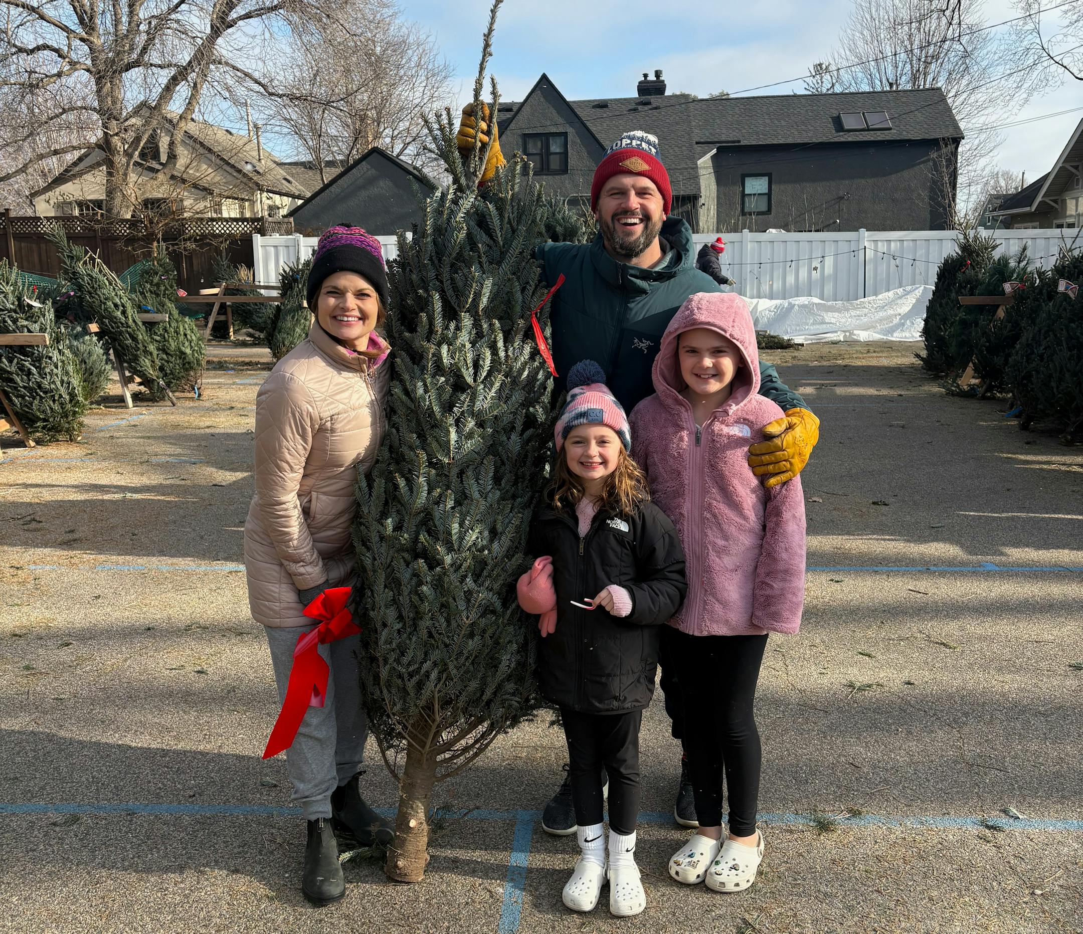 The family of Harper Moyski, far right, poses with their Christmas tree at the Annunciation tree lot in December 2024.