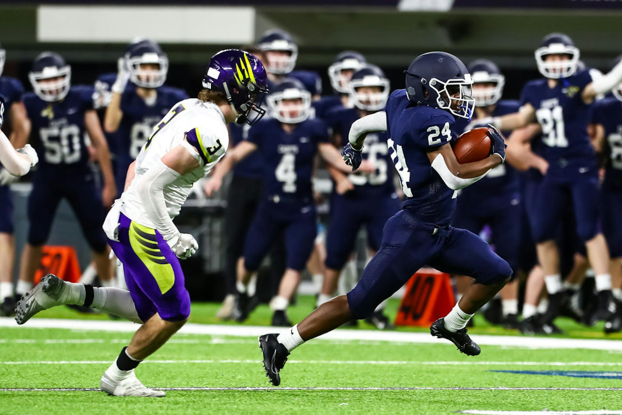 St. Thomas Academy Cadets running back Love Adebayo (24) runs with the ball past Chaska Hawks defensive back Ben Courneya on Saturday at U.S. Bank Stadium.