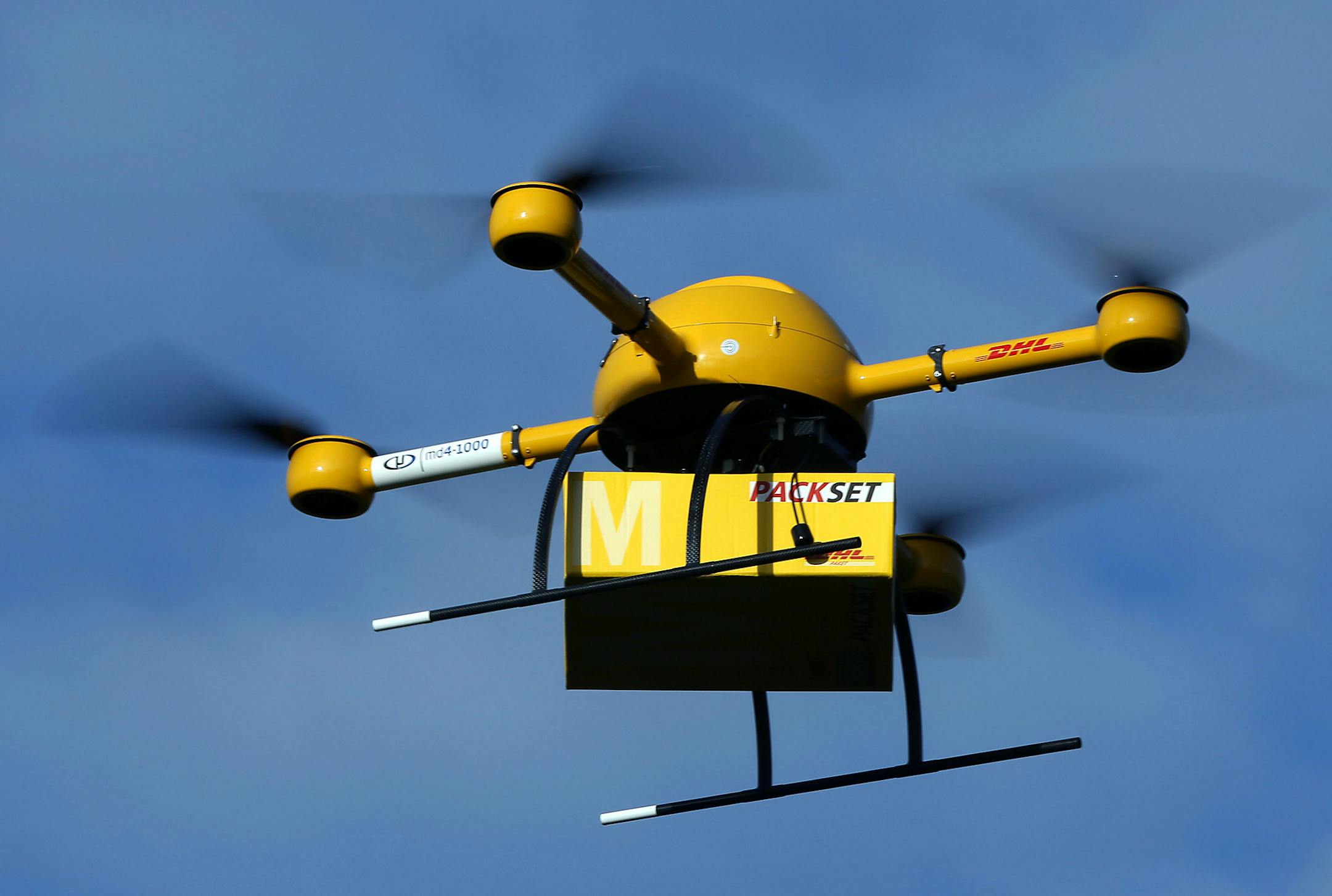 A drone with a small parcel flies in Bonn Germany, Monday Dec. 9, 2013. Germany's express delivery and mail company Deutsche Post DHL is testing a drone that could be used to deliver urgently needed goods to hard-to-reach places. The small pilotless helicopter was to fly a package of medicine Monday from a pharmacy in the town of Bonn to the company's headquarters on the other side of the Rhine River. The aircraft can carry up to 3 kilograms (6.6 pounds). (AP Photo/dpa,Oliver Berg)