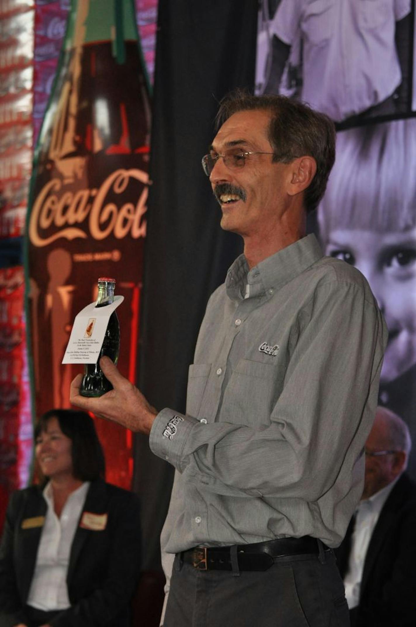 Cutline: LeRoy Telstad, vice-president and general manager at the Coca-Cola Bottling Company of Winona, held up the last 6.5-ounce returnable bottle to be filled and capped at the plant. It went for $2,000 at a private auction for executives, distributors and Coke fans held earlier this week.