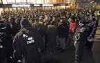 FILE - In this Dec. 31, 2016 file photo police officers surround a group of men in front of the Cologne, western Germany, main station, where a string