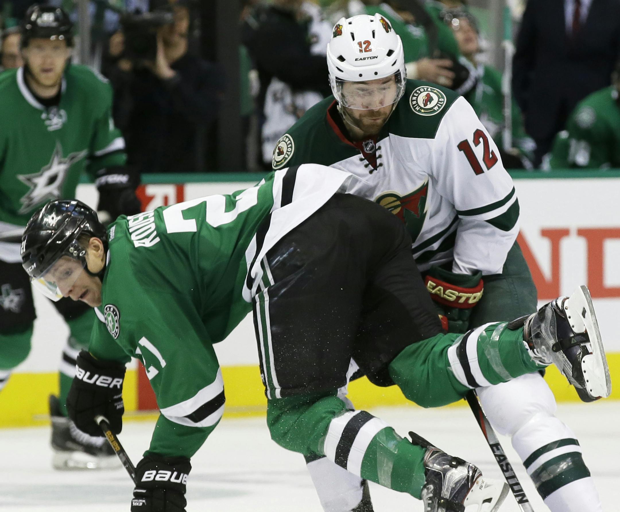 Dallas Stars left wing Antoine Roussel (21) reaches for the puck in front of Minnesota Wild right wing David Jones (12) during the third period of Game 1 in a first-round NHL hockey Stanley Cup playoff series Thursday, April 14, 2016, in Dallas. The Stars won 4-0. (AP Photo/LM Otero)