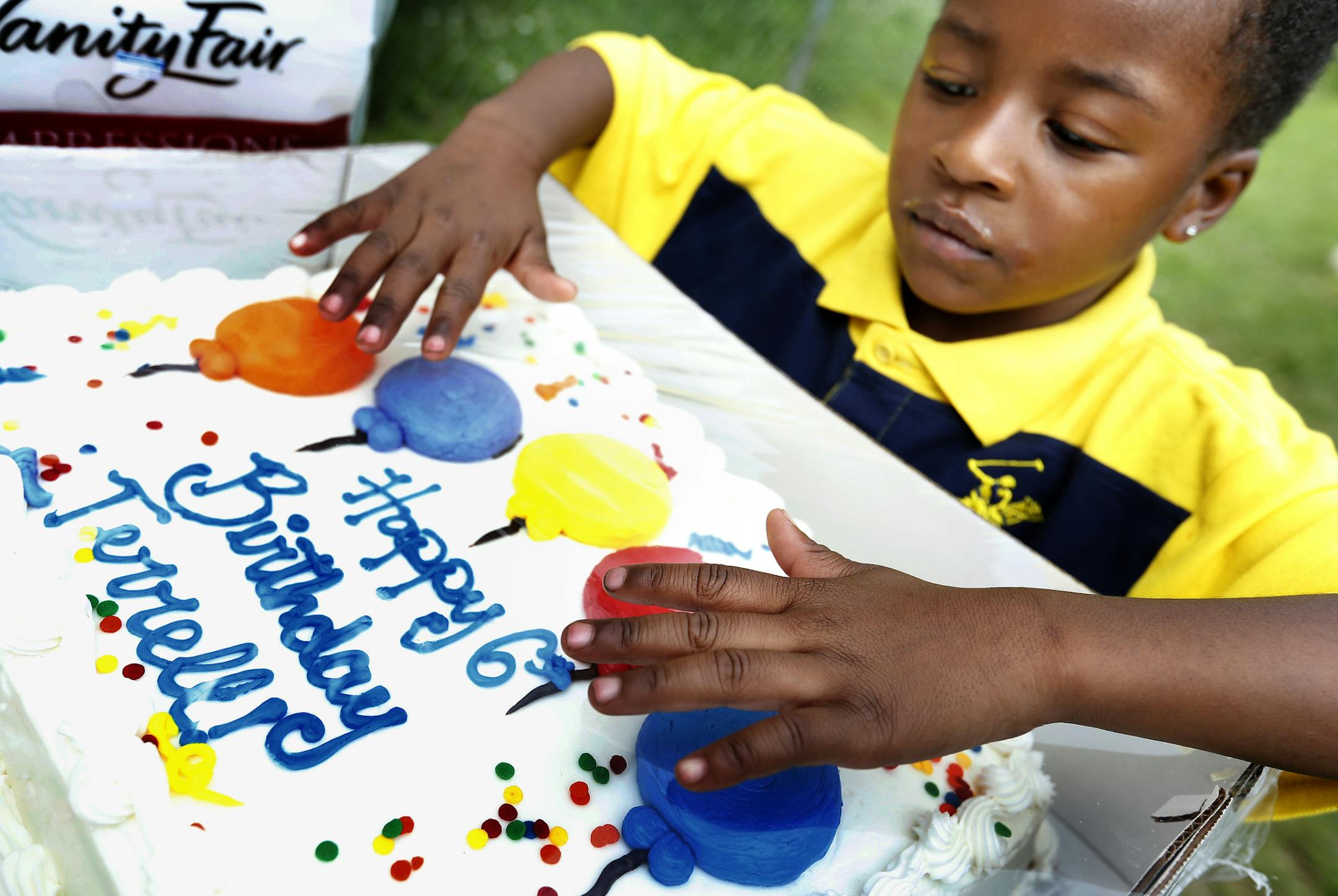 Marrell Mayes, 4, brother of Terrell Mayes Jr., looked at his Birthday cake during a community celebration for Terrell on Tuesday. The family and community held a celebration in a lot next to the former home Terrell Mayes Jr., to commemorate what would have been his sixth birthday on Tuesday. Terrell Mayes Jr., was struck and killed by a stray bullet in his Minneapolis home in 2011. ] CARLOS GONZALEZ cgonzalez@startribune.com - July 29, 2014 , Minneapolis, Minn., the North Minneapolis community