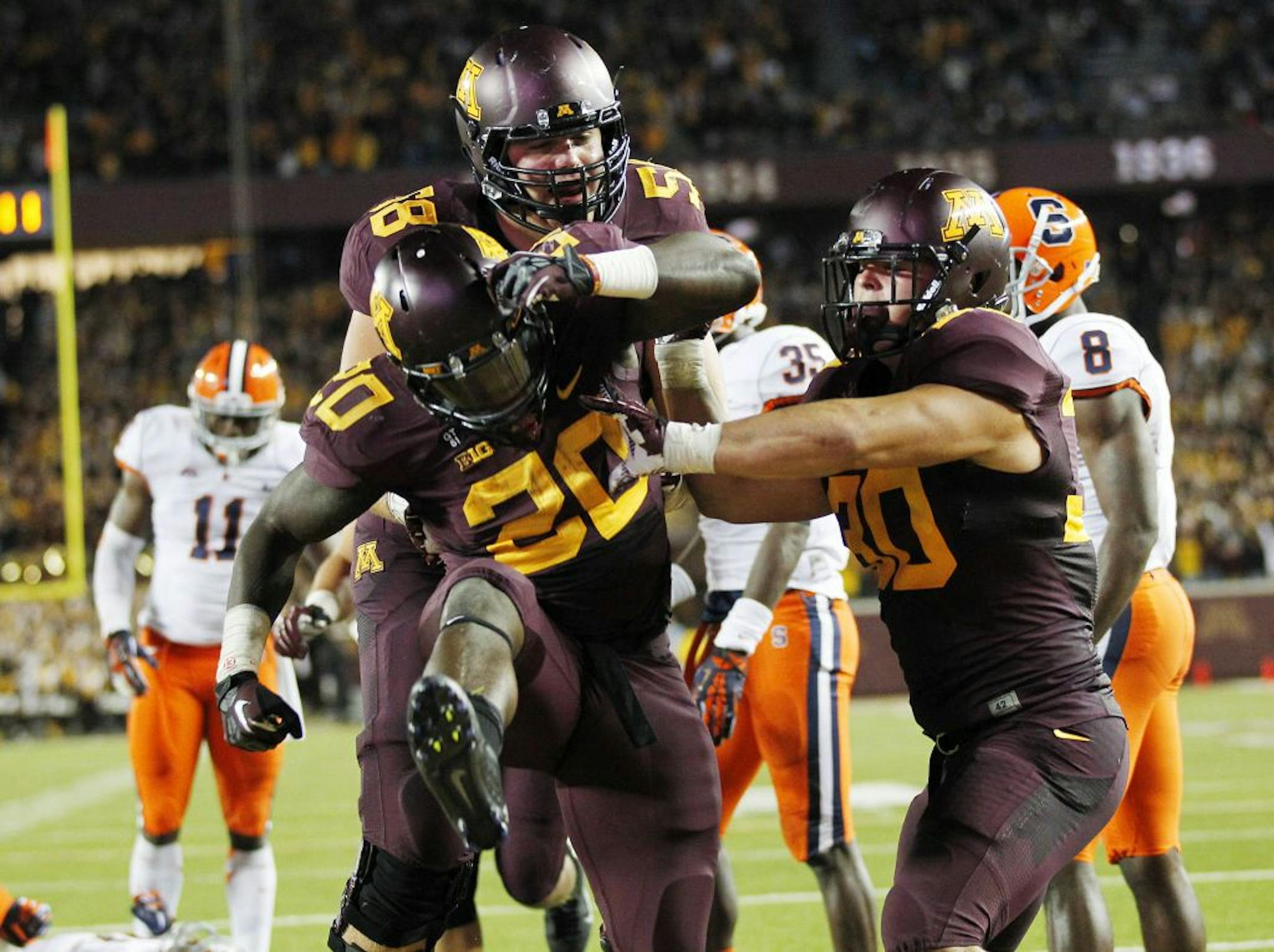 Minnesota running back Donnell Kirkwood celebrates with teammates Ed Olson (58) and Mike Henry, right, after Kirkwood's rushing touchdown in the second half of an NCAA college football game against Syracuse in Minneapolis on Saturday, Sept. 22, 2012. Minnesota defeated Syracuse 17-10.