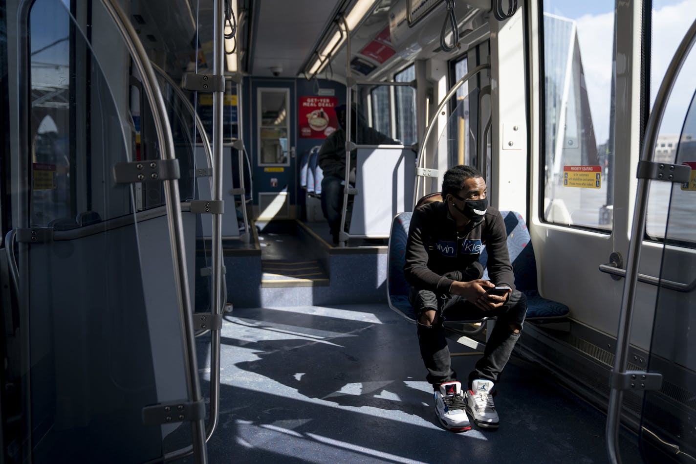 Ocyress Delarosa rides an almost empty Light Rail during the p.m. rush hour to meet someone in Minneapolis, Monday, April 13, 2020, during the coronavirus outbreak. (Renee Jones Schneider/Star Tribune via AP)