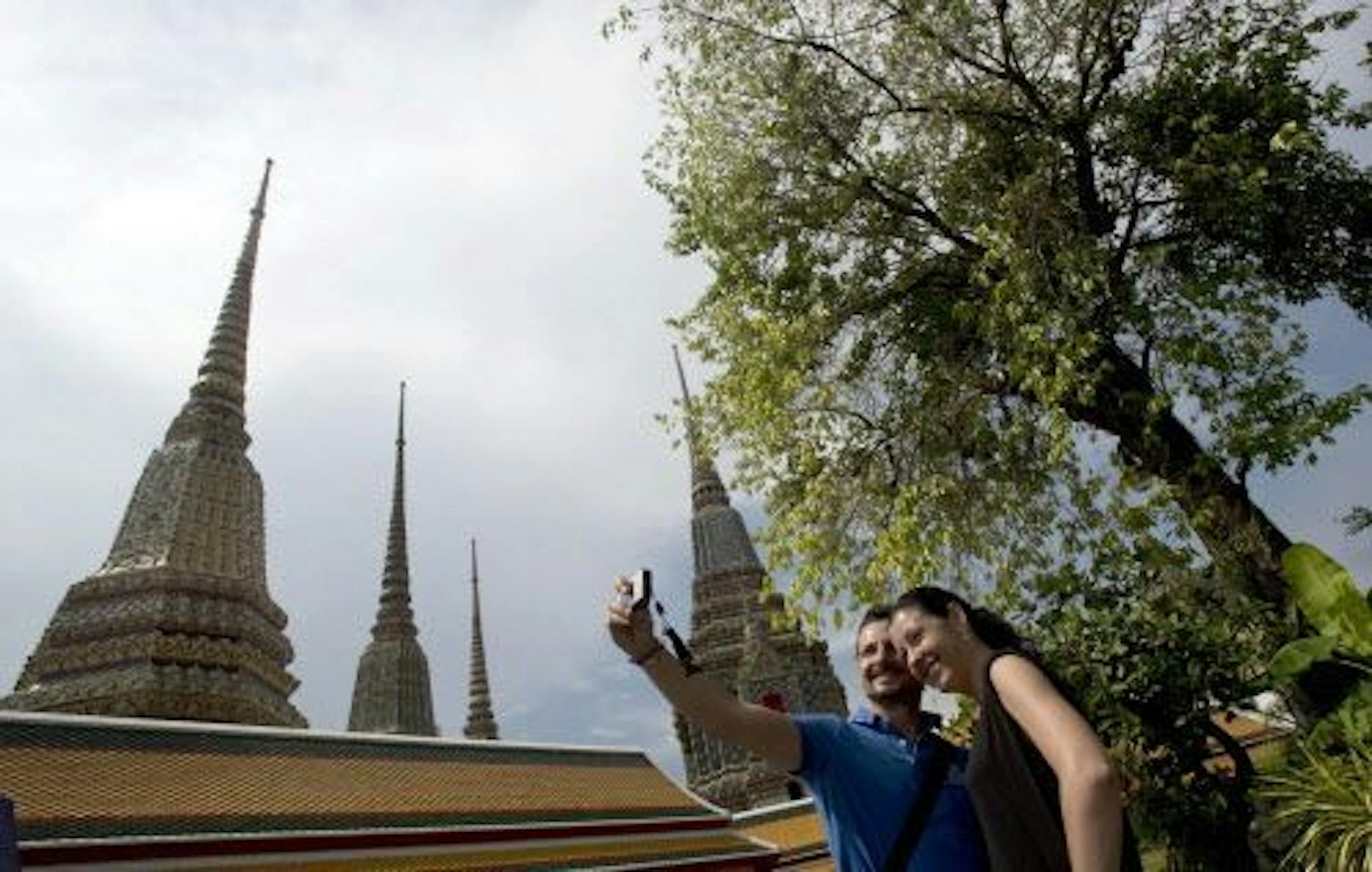 A couple of Western tourists snap a selfie at a Wat Pho temple in Bangkok, Thailand Tuesday, May 27, 2014.