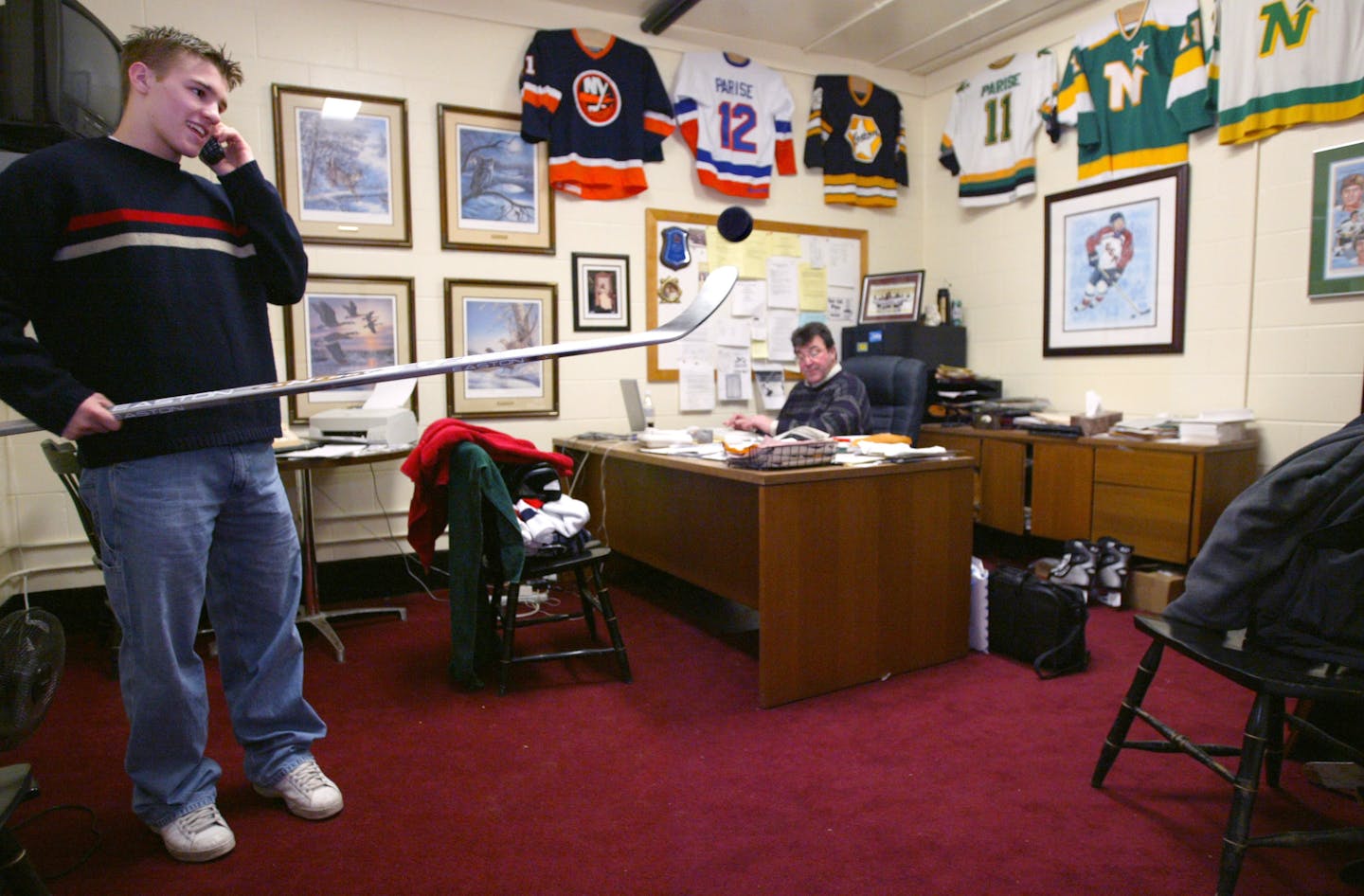 In this 2003 file photo, University of North Dakota star Zach Parise talks with a friend on the phone and plays with a puck in his father J.P. Parise's office. At the time, J.P. was the director of hockey and head coach of the Bantam Tier 1 team at Shattuck-St. Mary's School.