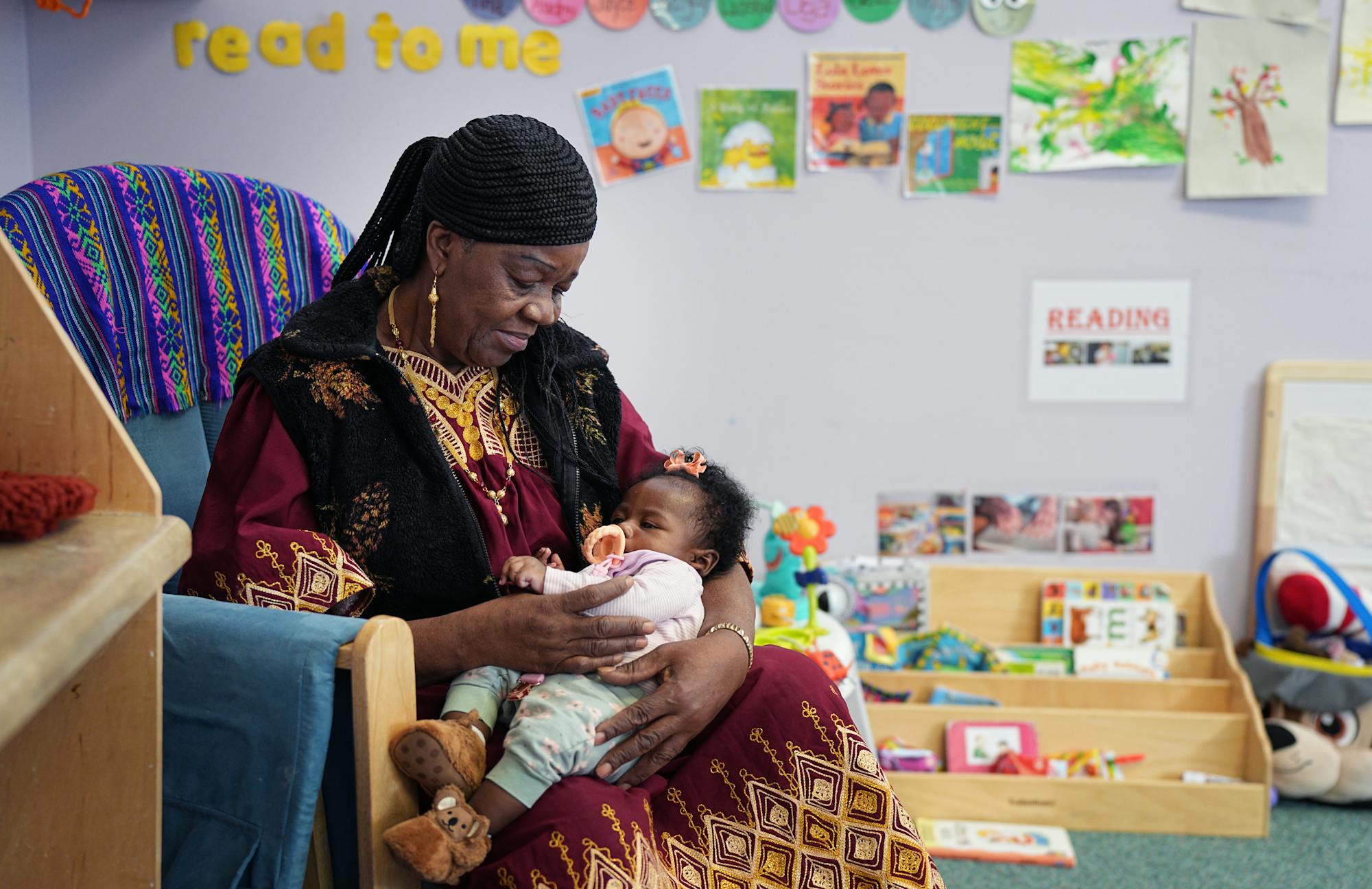 68-year-old Irene Ford sits in a chair and holds a baby as part of her foster grandparent volunteer work at the Northside Child Development Center.