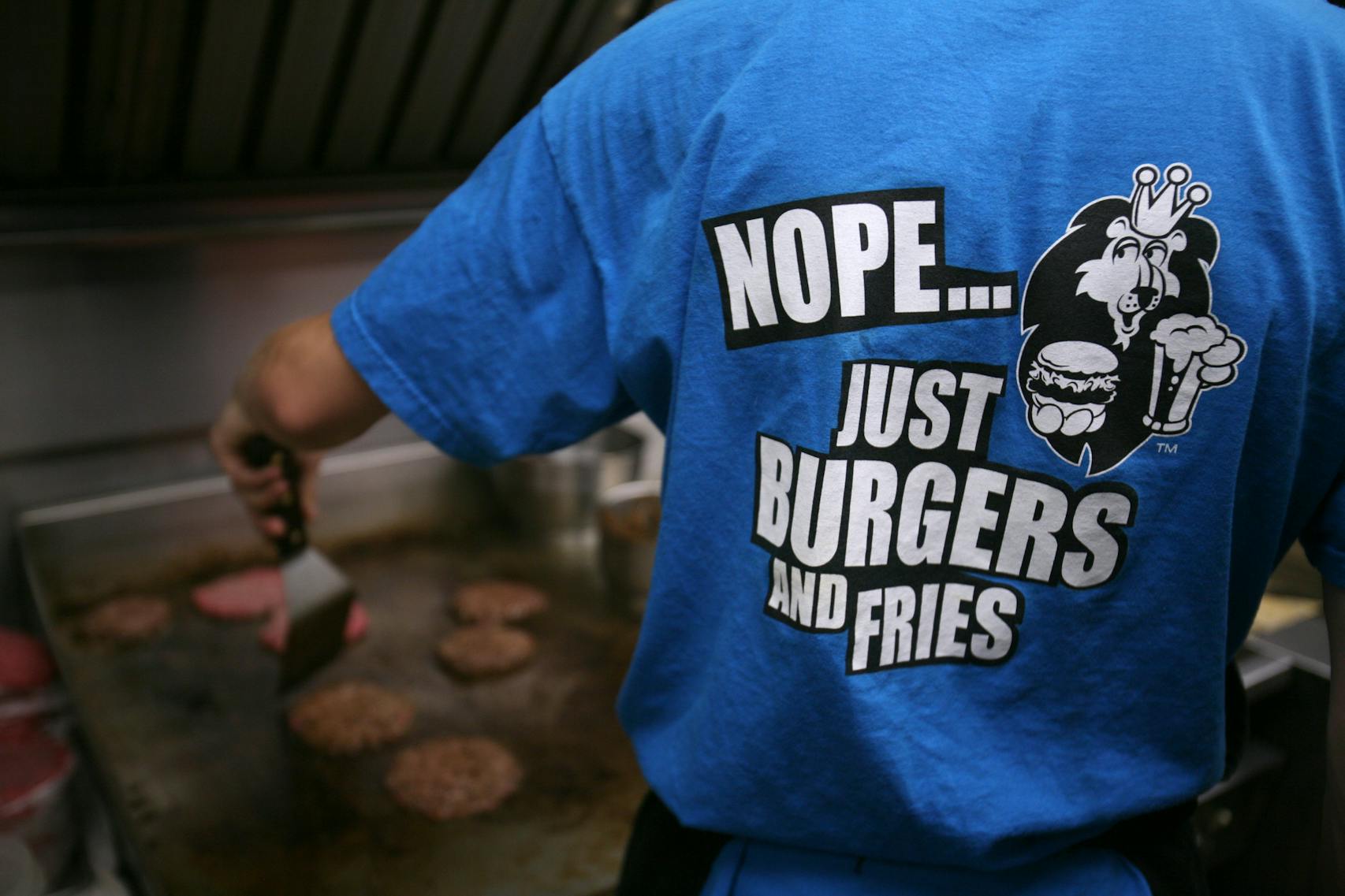 JEFF WHEELER ¥ jwheeler@startribune.com EDEN PRAIRIE - 10/11/07 - The Lions Tap is celebrating its 30th anniversary under the ownership of Bert and Bonnie Notermann next month. The Eden Prairie institution makes burgers and fries and not much else. IN THIS PHOTO: Cook Brian Garbowicz’s t-shirt sums up the Lions Tap’s mission as he flipped burgers Thursday night.
