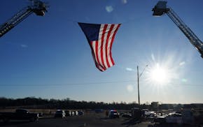 A giant American flag hung between two ladder trucks ahead of a memorial service for Burnsville police officers Paul Elmstrand, 27, Matthew Ruge, 27,
