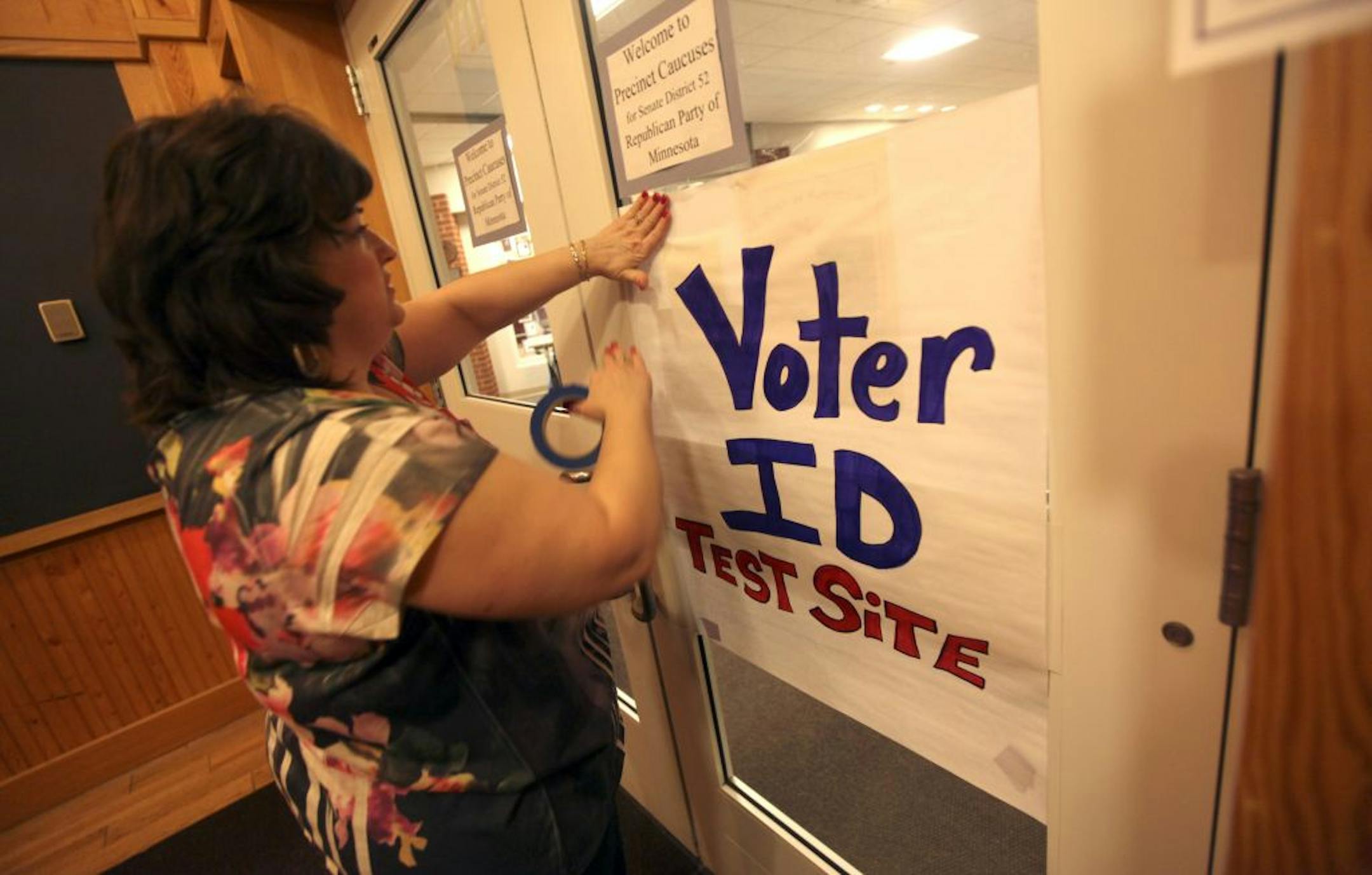 Cindy Westrup put up signs to lead caucus goers to the right places at the Republican precinct caucuses in Stillwater earlier this year. There, Republicans swiped driver's licenses through card readers to demonstrate a method of requiring photo IDs at the polls.