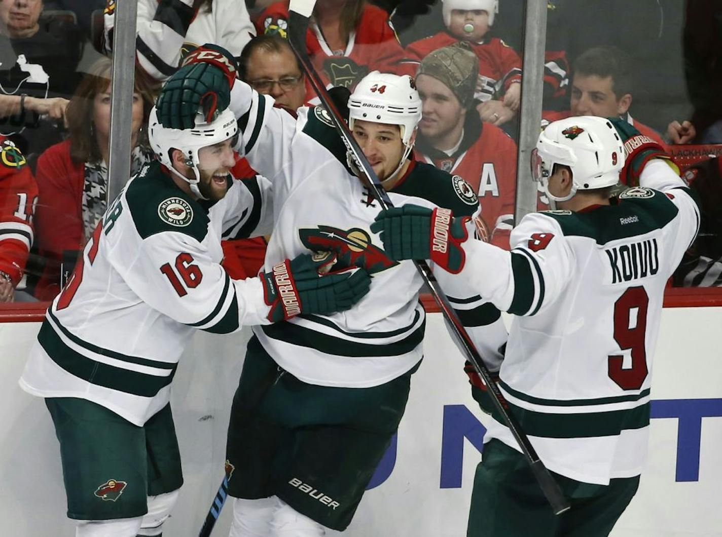 Minnesota Wild left wing Jason Zucker (16) celebrates with teammates right wing Chris Stewart (44) and center Mikko Koivu (9) a goal against the Chicago Blackhawks during the third period of an NHL hockey game Tuesday, April 7, 2015, in Chicago. The Wild won 2-1.