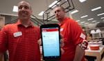 Store director Jake Seaquist, left, and food and beverage team leader Steve Noon, right, show the store device that will be used by Target employees t