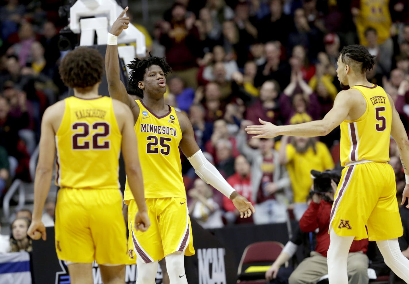 Minnesota's Daniel Oturu (25) reacts next to teammates Gabe Kalscheur (22) and Amir Coffey (5)