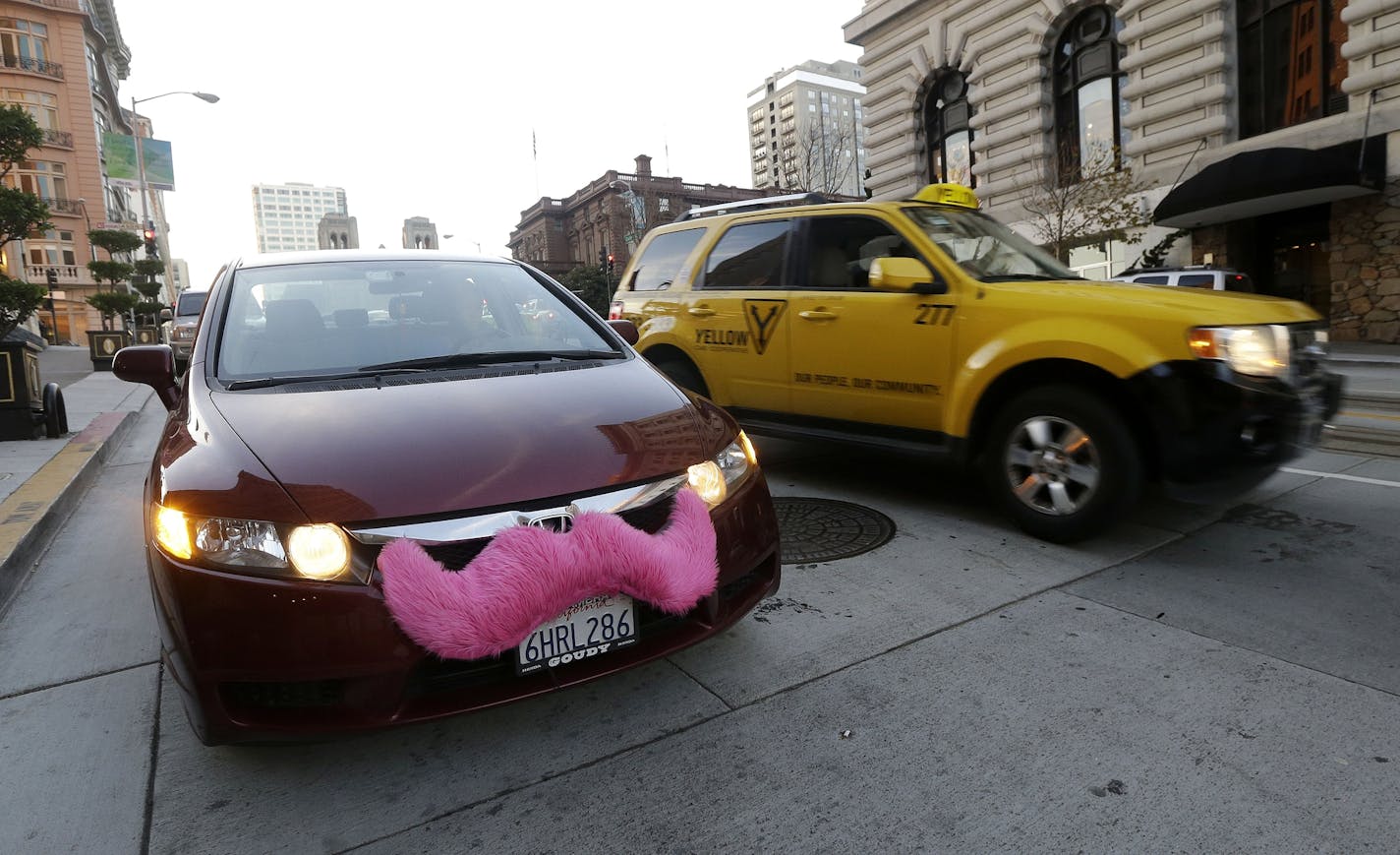 Jan. 4, 2013: Lyft driver Nancy Tcheou waits in her car after dropping off a passenger as a taxi cab passes her in San Francisco.