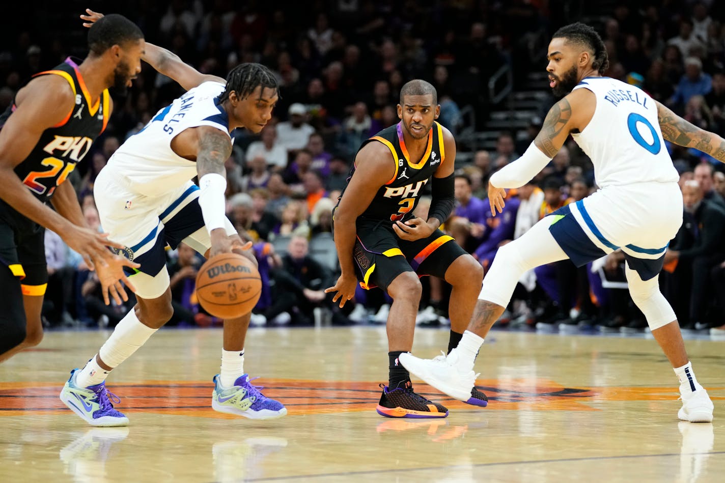 Phoenix Suns guard Chris Paul (3) passes the ball as Minnesota Timberwolves forward Jaden McDaniels and guard D'Angelo Russell (0) defend during the second half of an NBA basketball game, Tuesday, Nov. 1, 2022, in Phoenix. (AP Photo/Matt York)