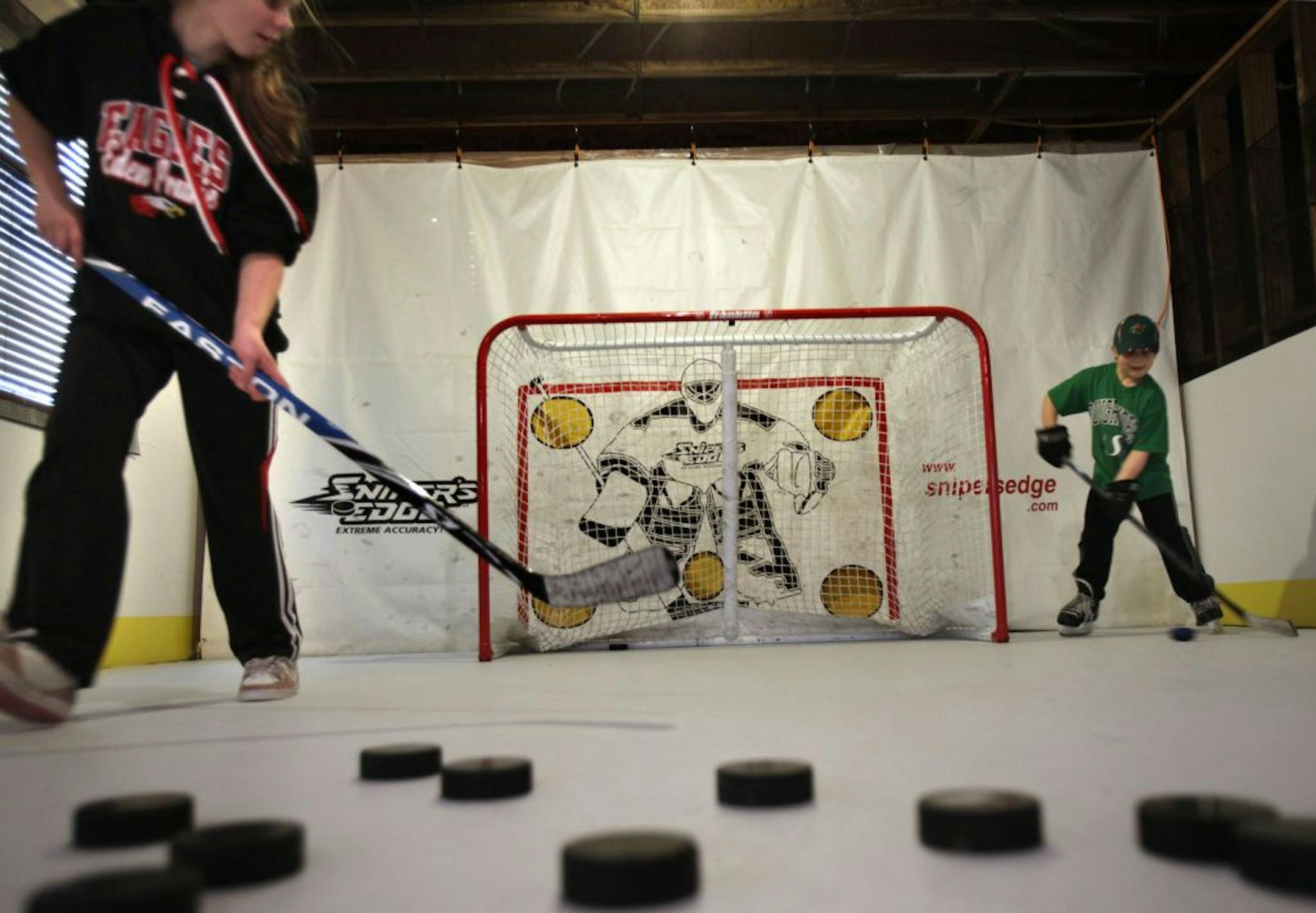Alexa Dobchuk (black shirt) gets ready to receive a pass from her brother Toran on their synthetic rink. The Dobchuk's put a synthetic rink in the basement of their home.