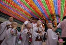 Boys with newly shaved heads walk under colorful lanterns after a service to celebrate Buddha's upcoming birthday at Jogye Temple in Seoul, South Kore