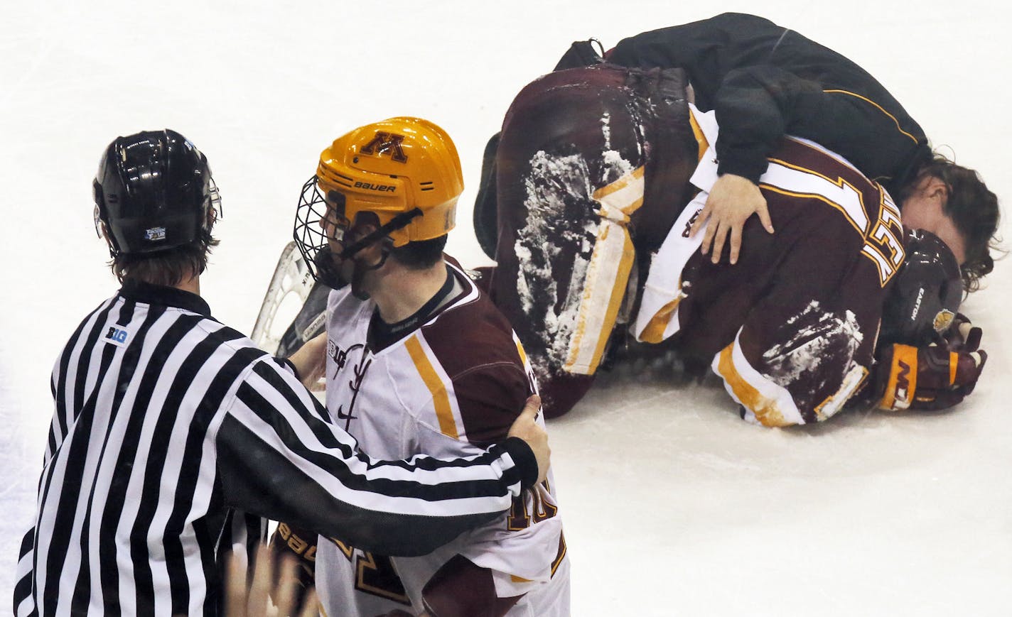 UMD's Austin Farley lay on the ice holding his head after a check by Minnesota Gophers Ben Marshall. Marshall was given a major penalty and ejected from the game as a result of the hit. An official led Marshall, left, to the penalty box and eventually off the ice as Farley was attended to by medical staff. (MARLIN LEVISON/STARTRIBUNE(mlevison@startribune.com)