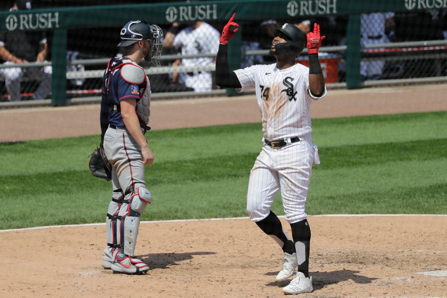 Chicago White Sox's Eloy Jimenez, right, celebrates after hitting a solo home run as Twins catcher Mitch Garver looks to the field during the fifth inning