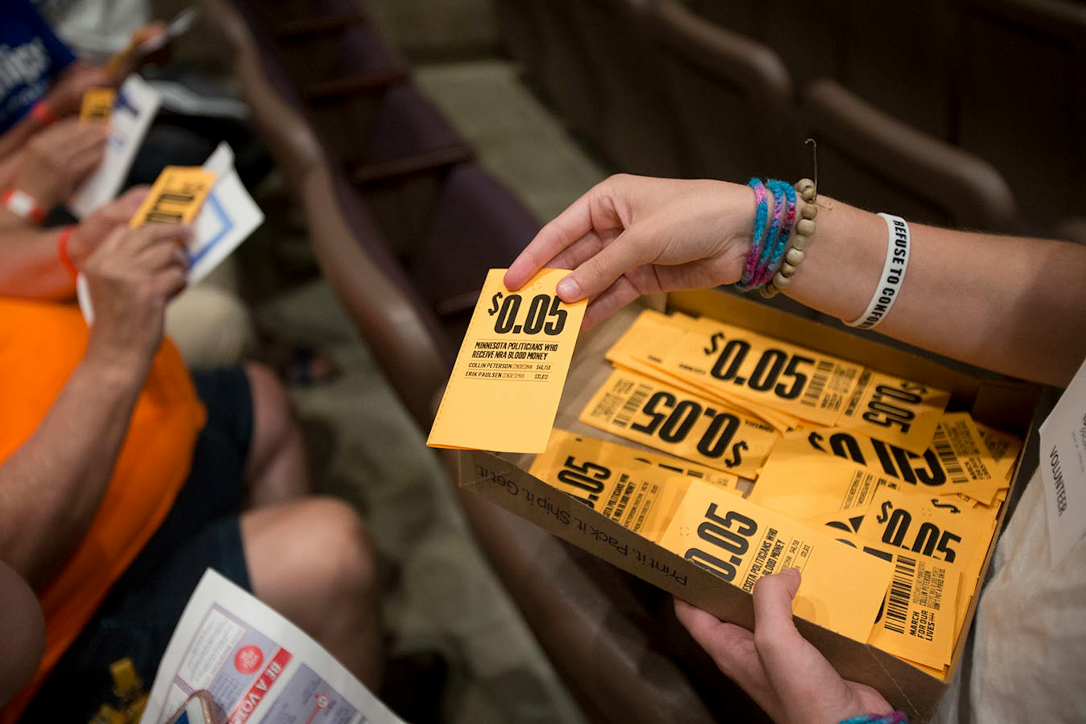 Sydney Lewis hands out small $0.05 coupons representing how many students there are in Minnesota divided by the amount of money Minnesota Congressmen Erik Paulsen and Collin Peterson receive from the NRA.