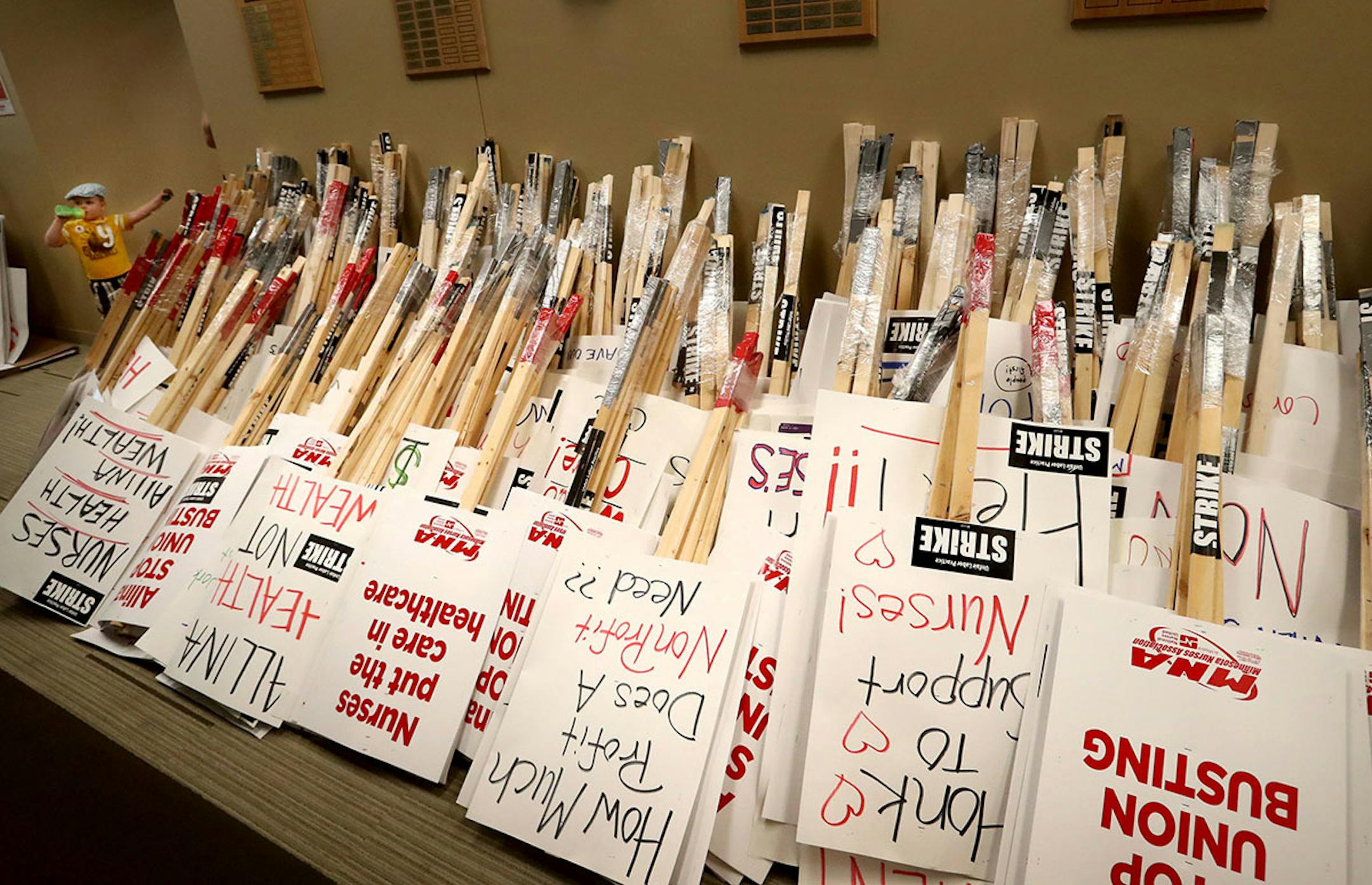 Dozens if not hundreds of picketing signs sit in the MNA headquarters hallway as Cooper Cunningham, 2 1/2, enjoyed milk in a sippy cup. MNA nurses, Minnesota Nurses Association employees and family members joined forces at the MNA headquarters to make posters for picketing Saturday, June 18, 2016, should a strike happen Sunday at five Twin Cities Allina Health facilities. Cooper' mother Shannon Cunningham is a MNA employee.