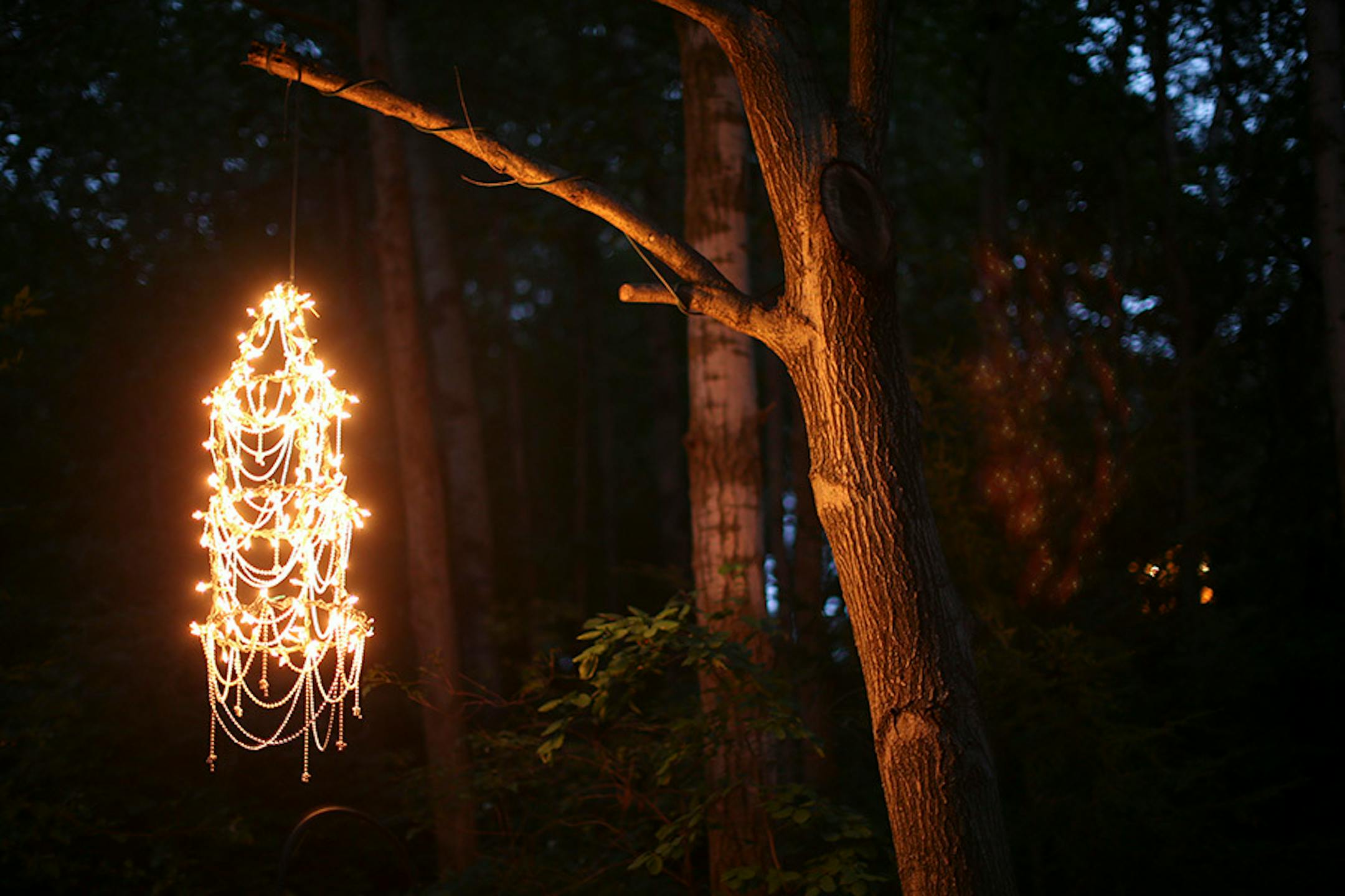 The tomato cage chandelier is wrapped with Christmas lights.