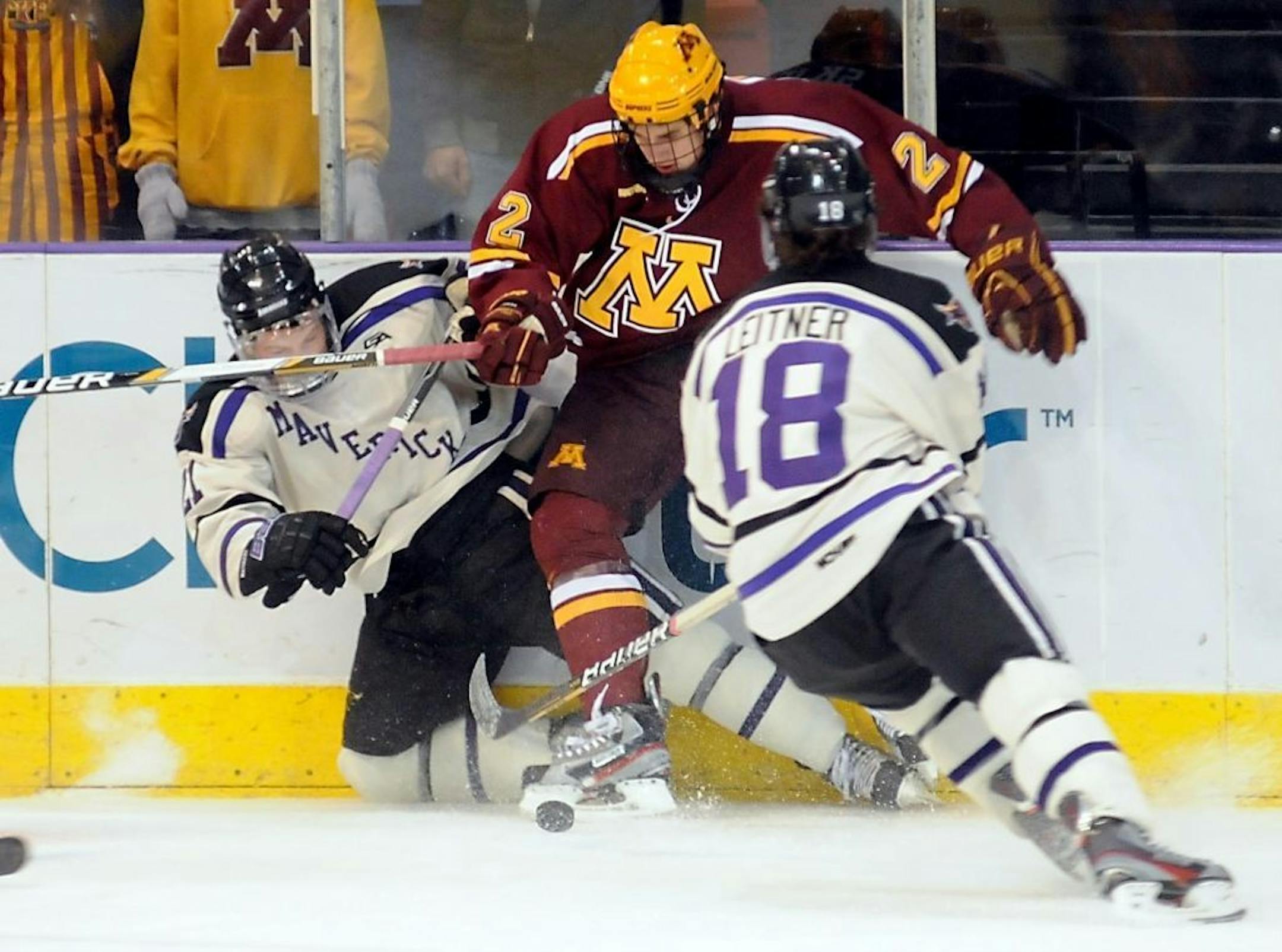 Minnesota's Brady Skjei kicks at the puck as Minnesota State, Mankato's Chase Grant, left, and Matt Leitner (18) defend during the first period of a college hockey game Saturday, Nov. 3, 2012, in Mankato, Minn.