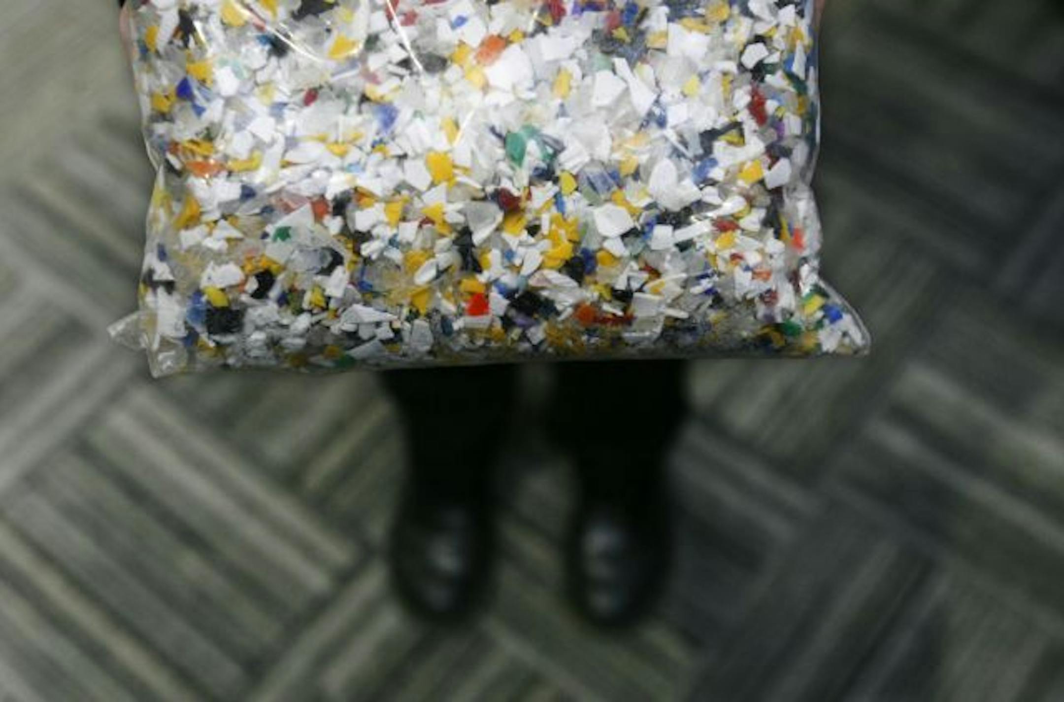 Plastic caps that were cleaned and ground up in the recycling process held by Deb Darling, Aveda caps program manager.
