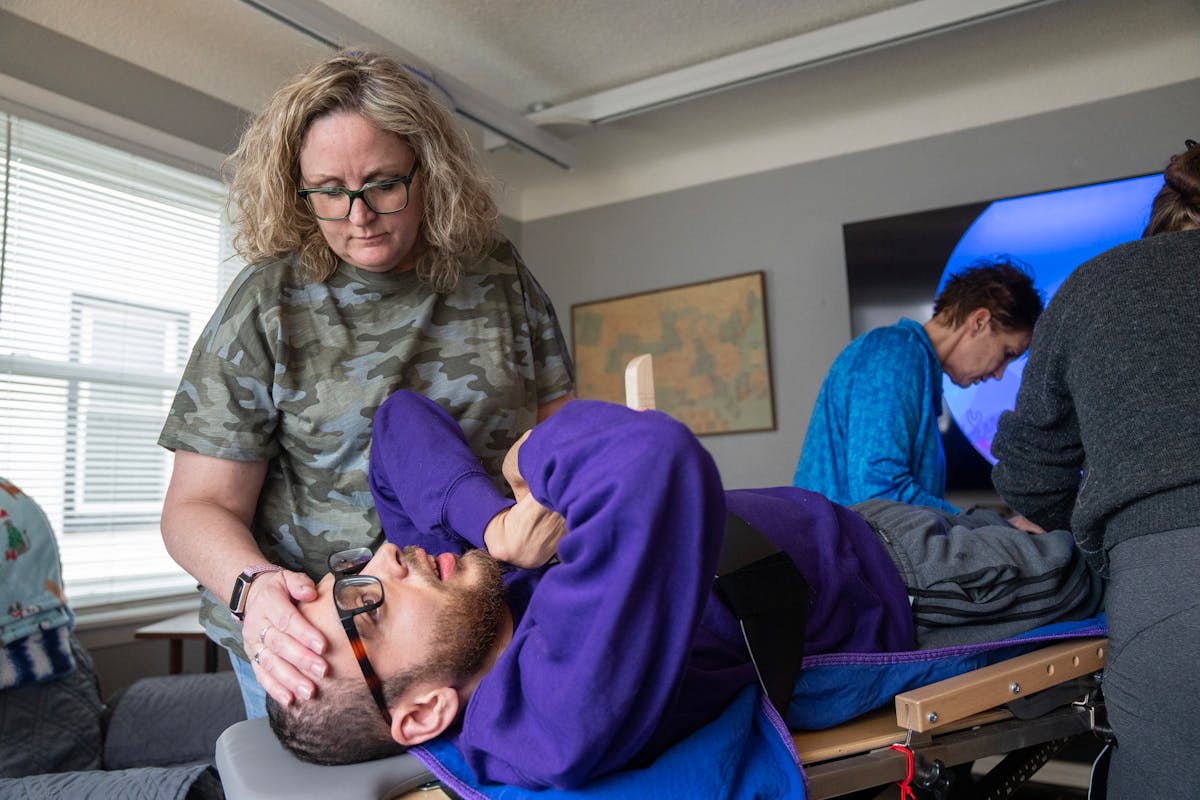 Kathy Ware, calms son Kylen, 29, as he is secured to a stander as part of his physical therapy at their South St. Paul home. The stander helps Kylen, 