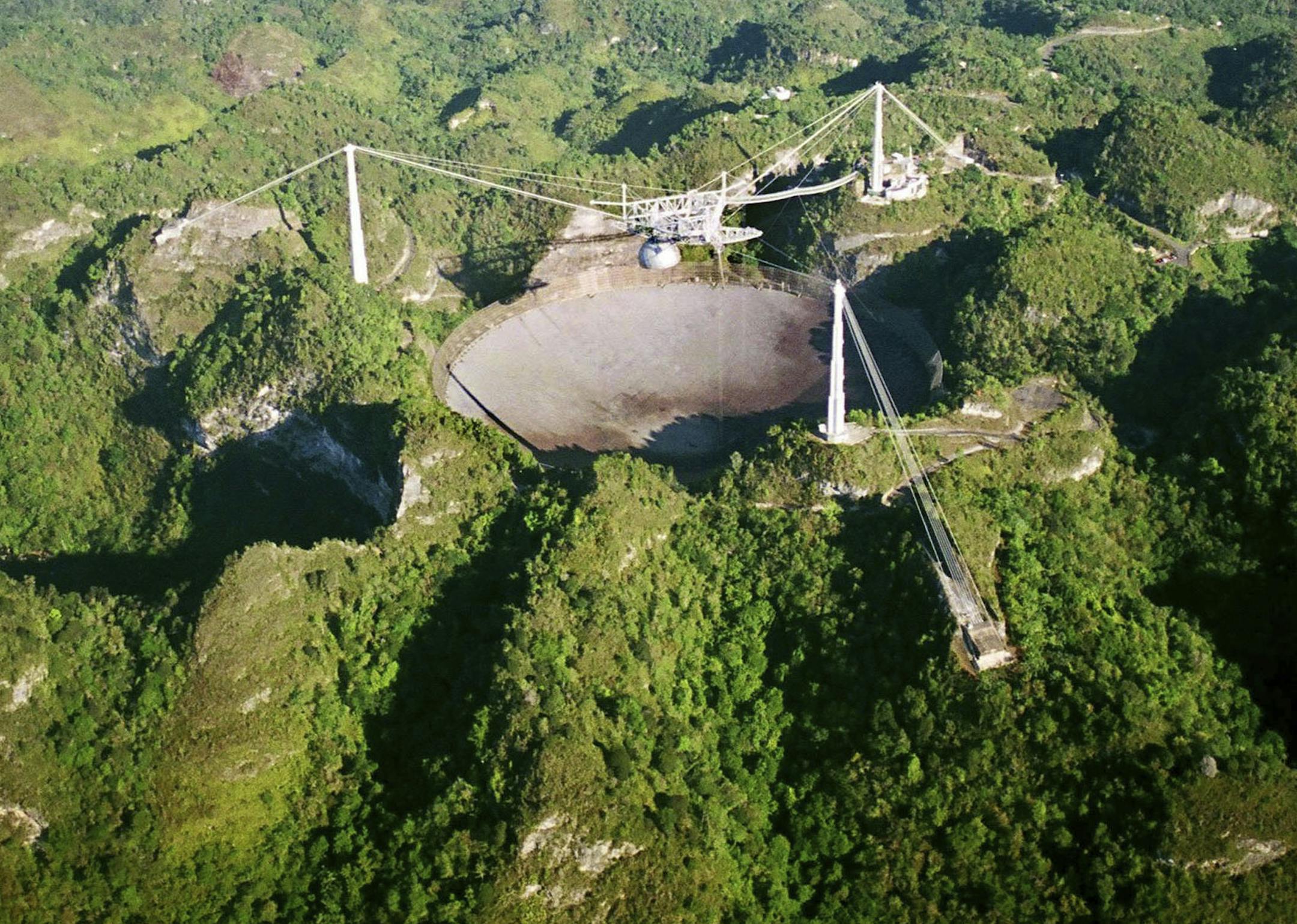 FILE- In this March 26, 2003, file photo, the world's largest radio telescope is seen from the air, at the Arecibo Observatory, in Puerto Rico. The future of one of the worldís largest single-dish radio telescopes has been called into question after the U.S. National Science Foundation announced it was formally seeking someone to operate the Arecibo Observatory in Puerto Rico. The Wednesday, Jan 25, 2017, announcement comes as the federal agency runs out of funds to support the observatory.