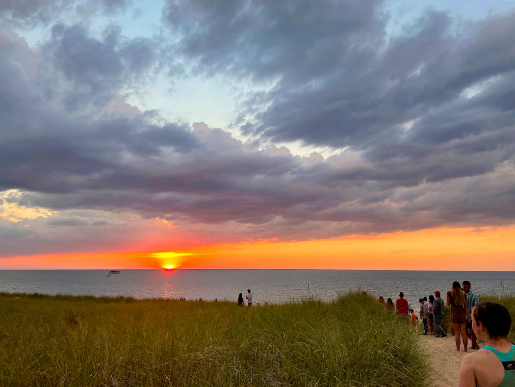 A sunset over Lake Michigan draws people to the beach in Michigan City, Ind. As Indiana rolls back protections for wetlands, other states that share waterways will also see the effects. 