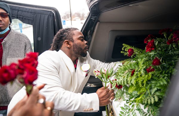 Cortez Rice, Jahmari Rice's father, hands out roses and flowers from his son's casket to other family members after his funeral Wednesday.