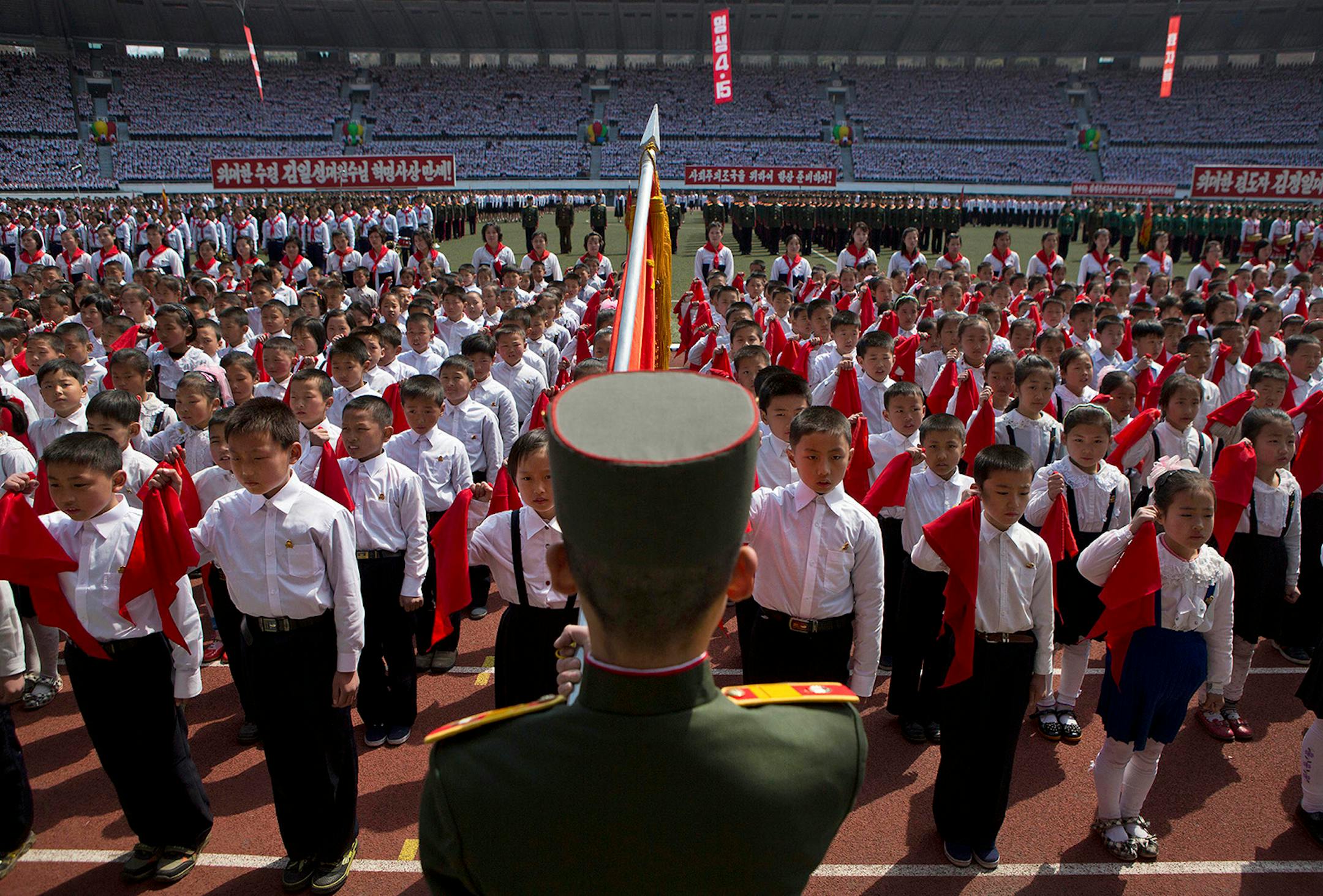 North Korean children hold up red scarves to be tied around their necks during an induction ceremony into the Korean Children's Union, the first political organization for North Koreans, held at a stadium in Pyongyang on April 12, 2013.