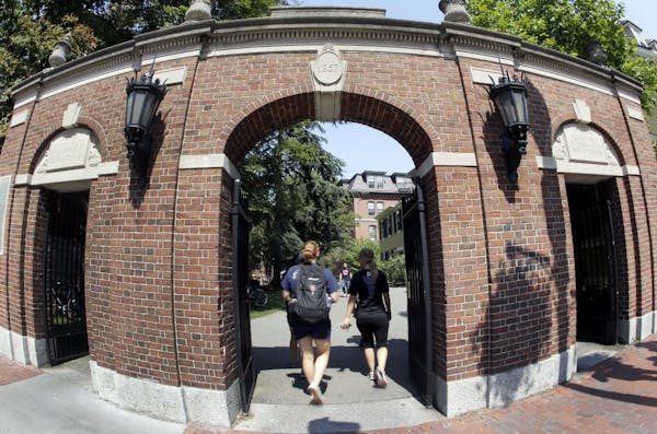 Pedestrians walk through a gate on the campus of Harvard University in Cambridge, Mass. Thursday, Aug. 30, 2012.