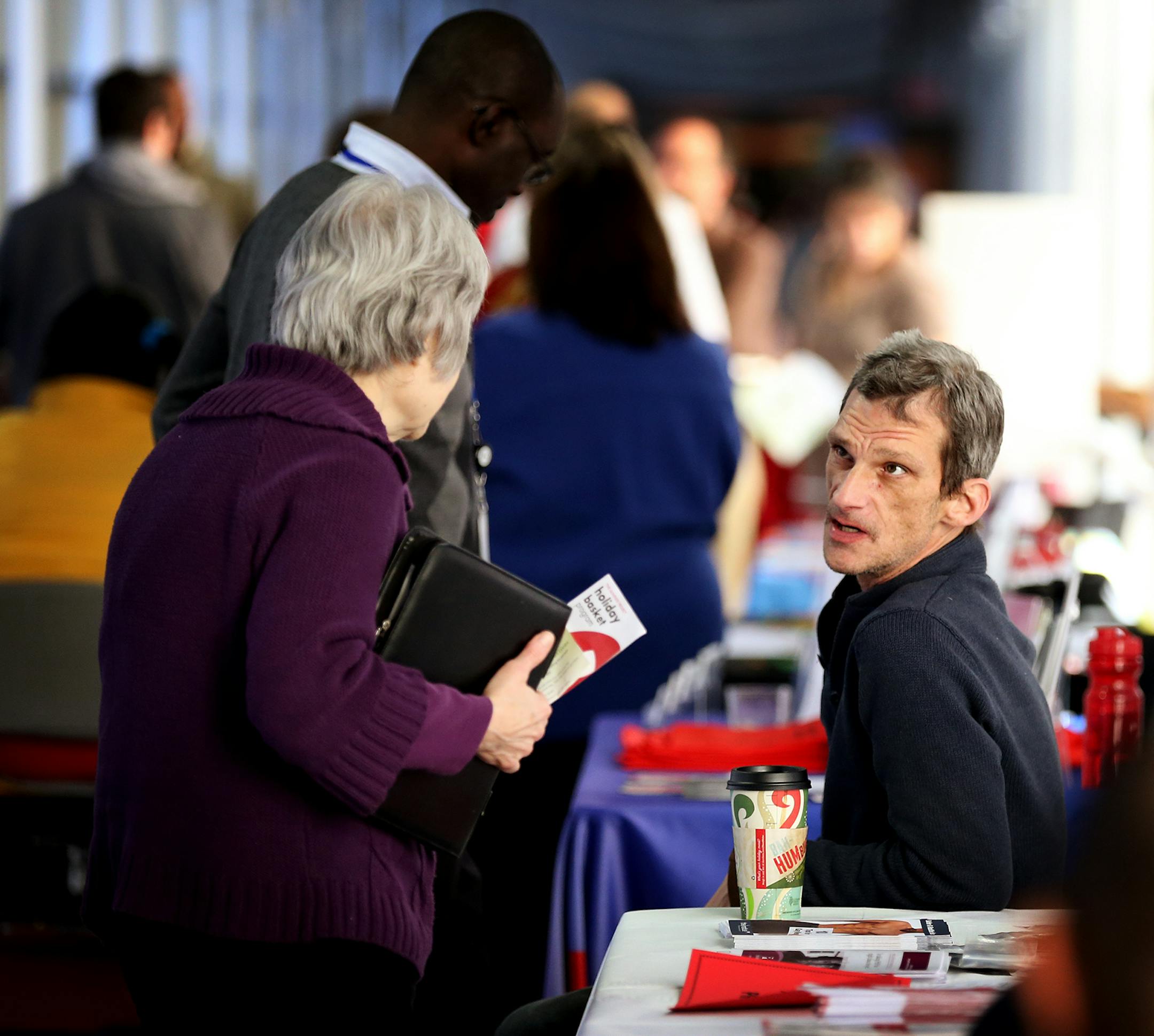 Joshua Conrade, an HIV outreach coordinator at The Aliveness Project, a direct service provider for HIV/AIDS patients, speaks to people from his booth during a World AIDS Day resource fair at Hennepin County Medical Center in Minneapolis on Monday, December 1, 2014. ] LEILA NAVIDI leila.navidi@startribune.com /