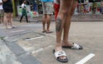 Residents step on measured tape placed outside a supermarket to practice social distancing as a precautionary measure against the spread of the corona